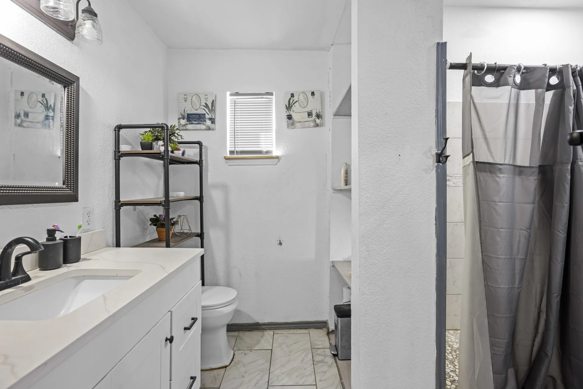 Full bath with vanity, marble look tiles, a textured wall, and a shower with shower curtain
