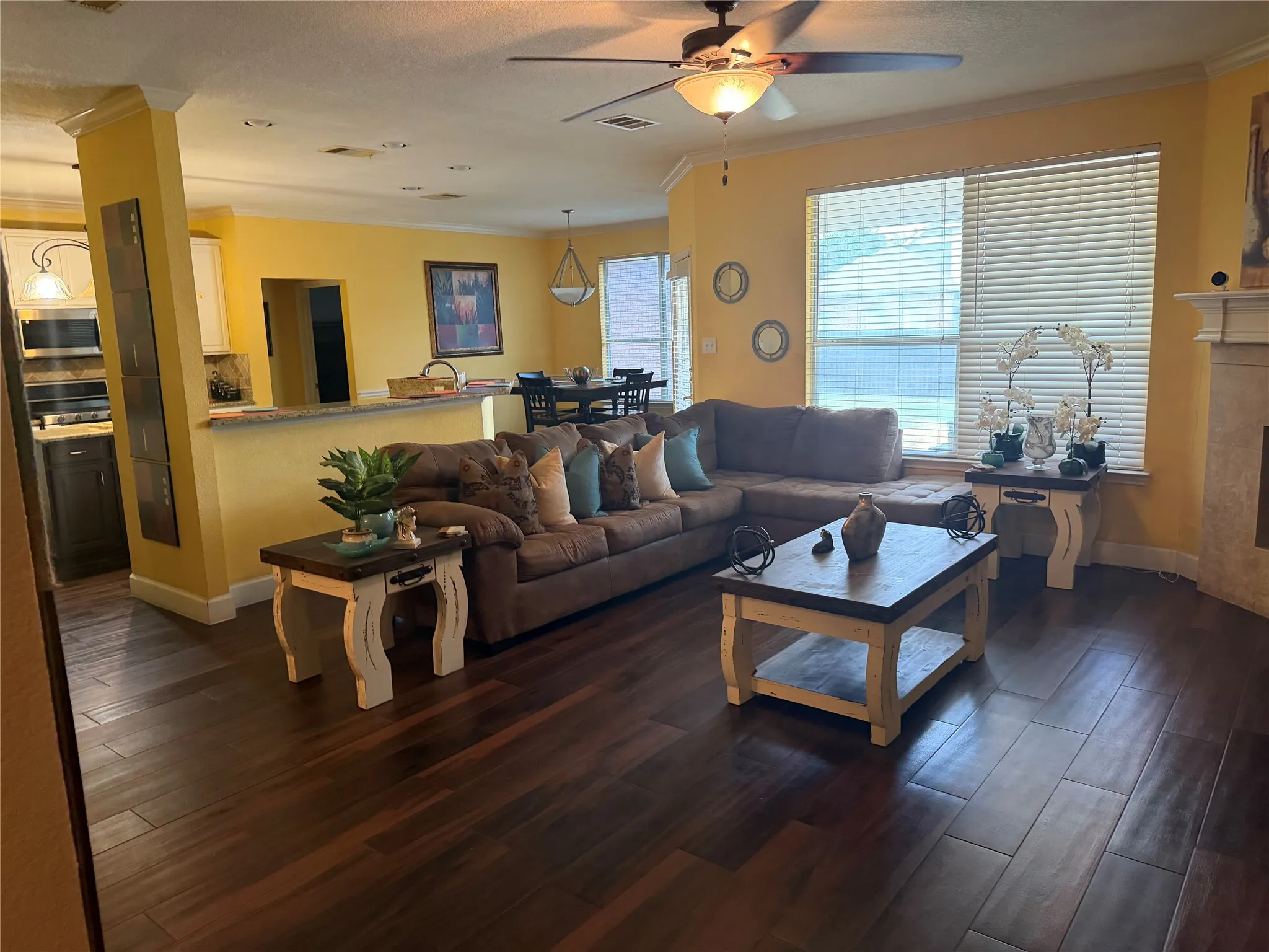 Wood-finish flooring throughout, ceiling fan with integrated lighting, multiple recessed lights, built-in breakfast bar, and multiple windows