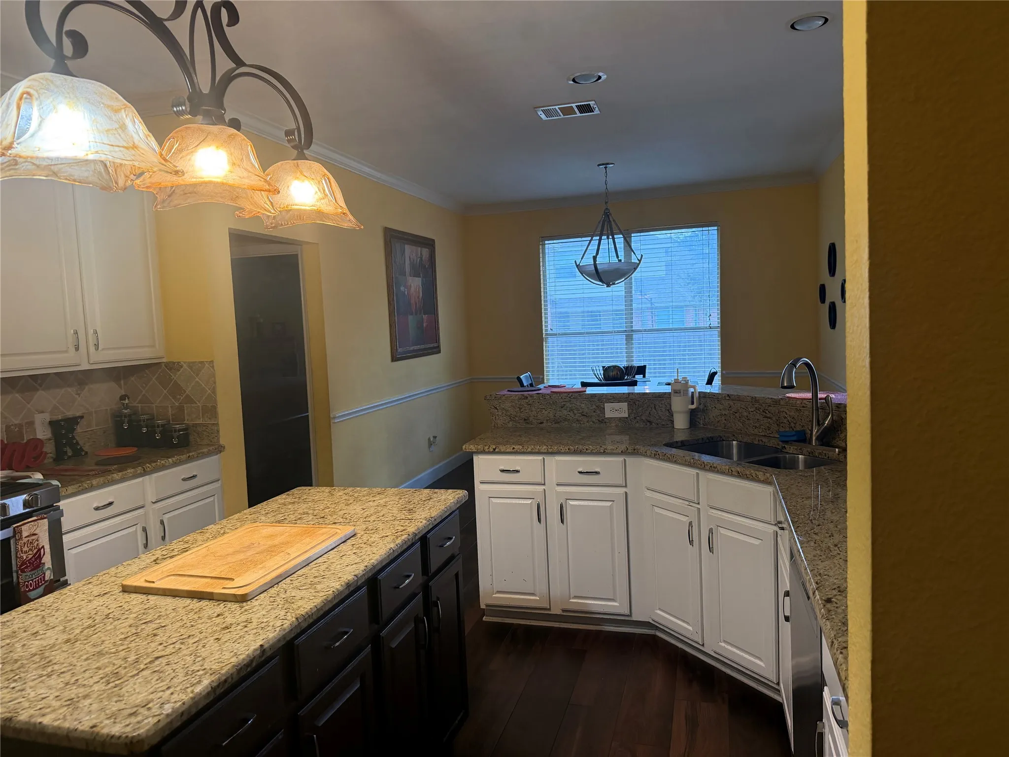 Kitchen featuring granite countertops, wood-finish flooring, white cabinetry, a kitchen island, and a double-basin sink