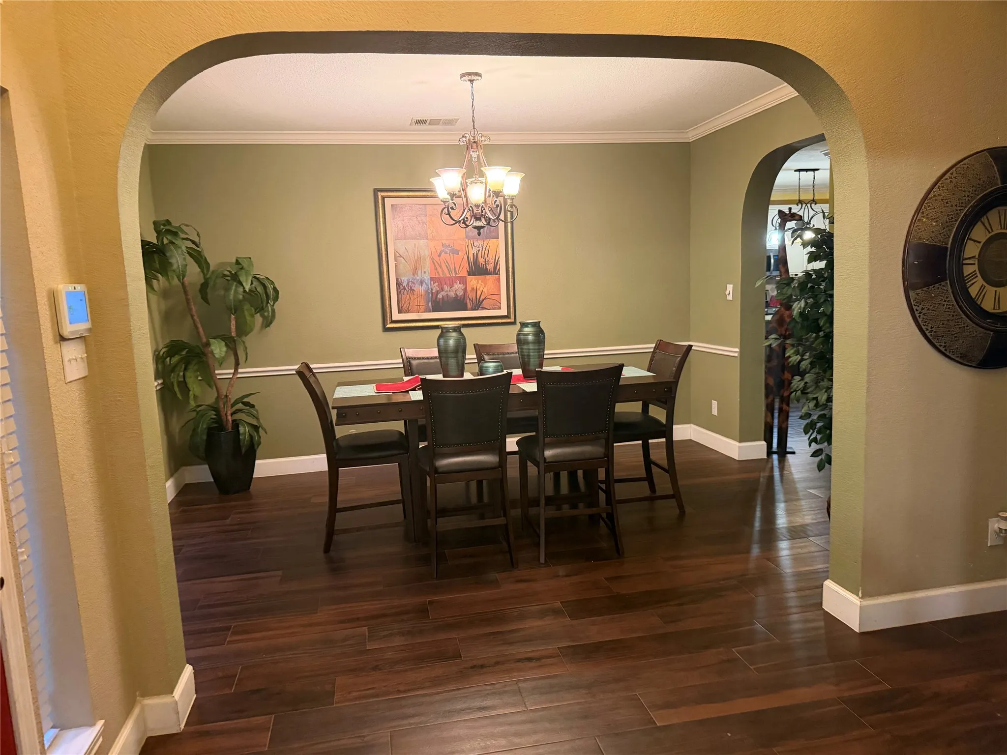 Formal dining area featuring wood-finish flooring, an arched entryway, and crown molding
