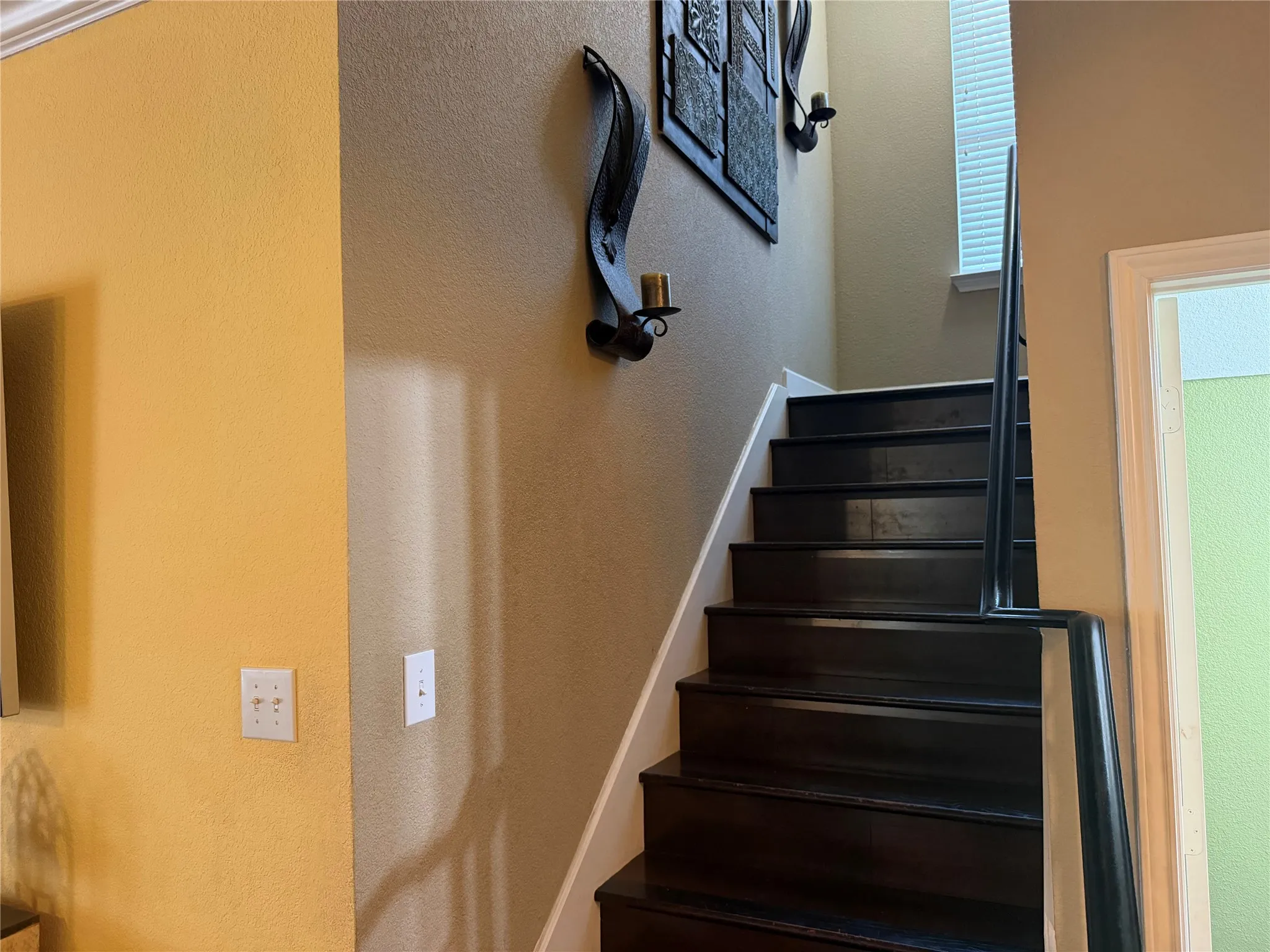 Dark wood-finish staircase with white risers and a black metal handrail