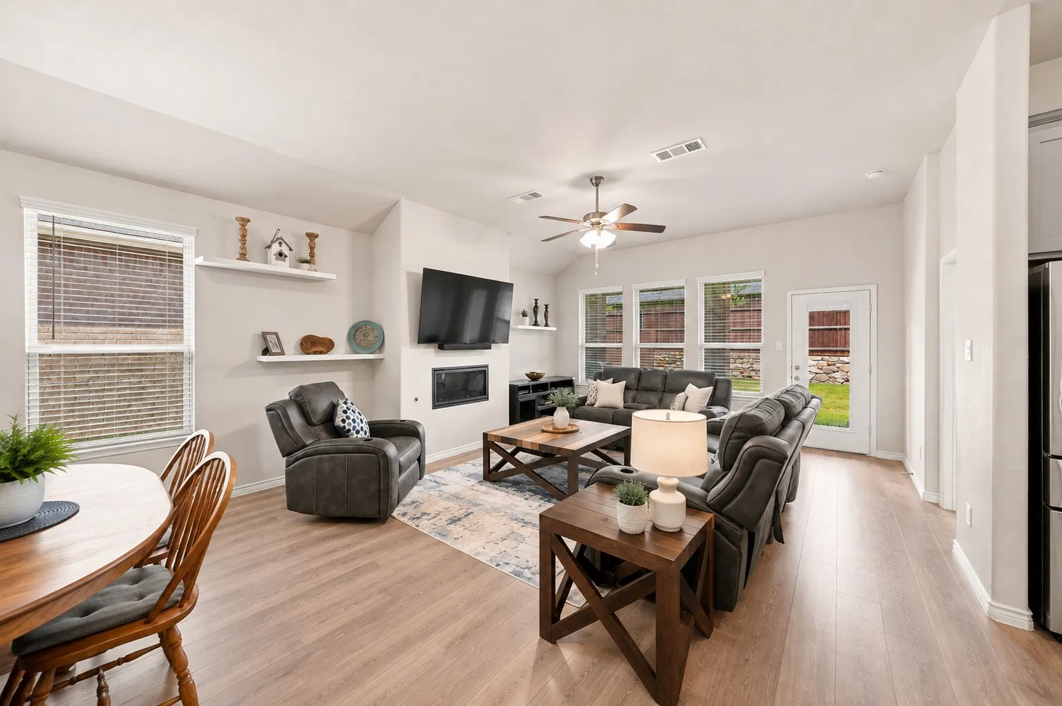 Open-concept living area featuring wood-finish flooring, a vaulted ceiling, and a ceiling fan