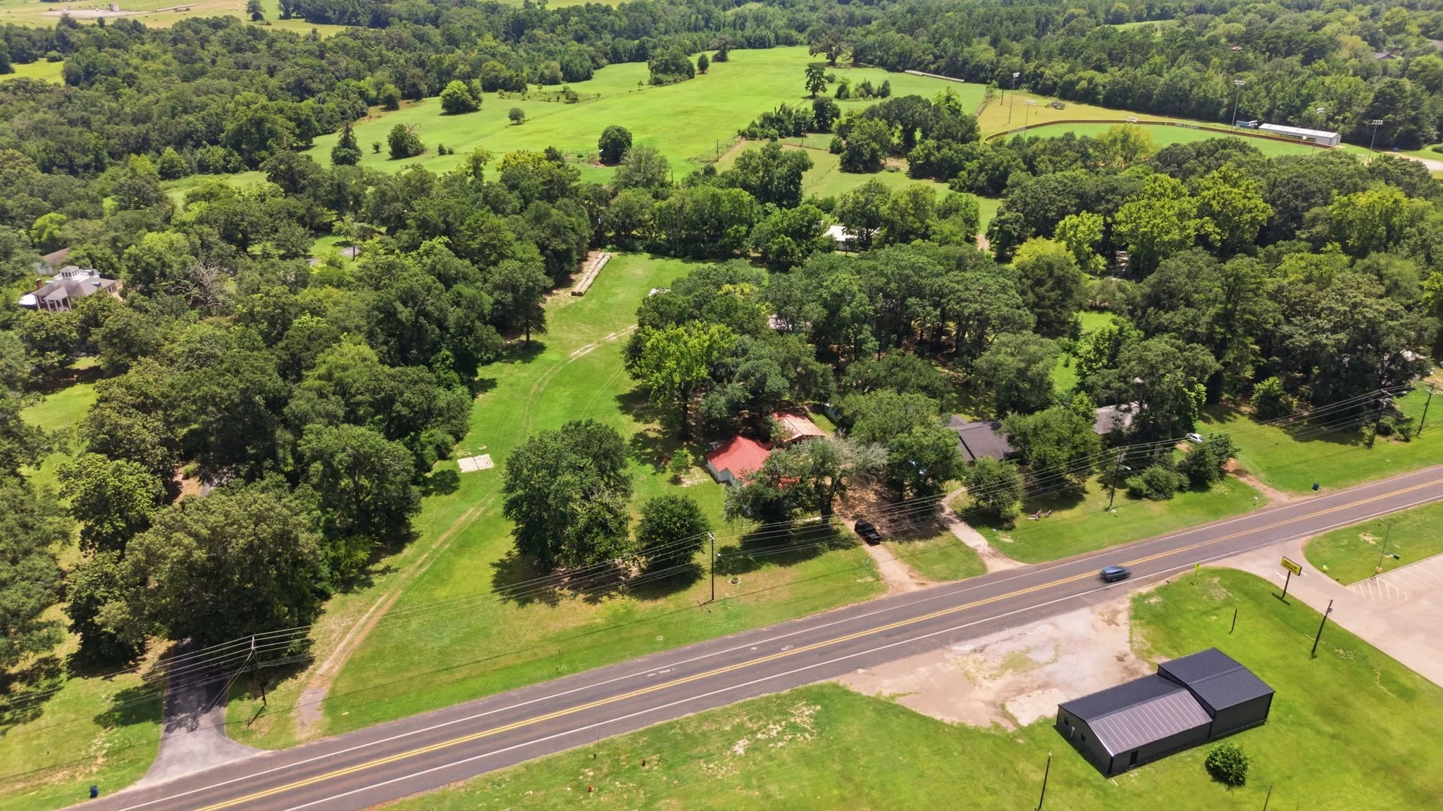 Expansive property featuring mature trees, open green spaces, and direct road frontage