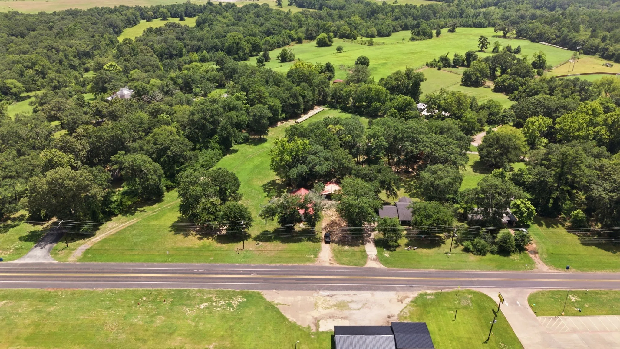 Expansive green landscape with significant tree coverage and multiple structures