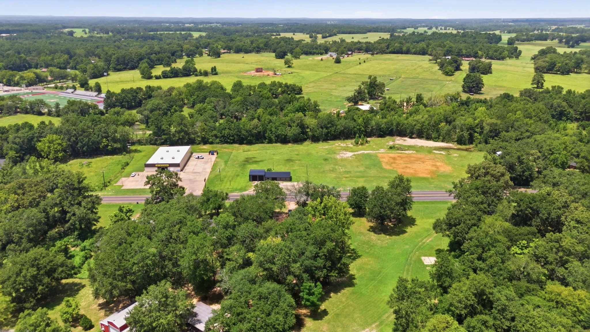 Expansive property featuring a commercial building, a residential structure, and extensive green space