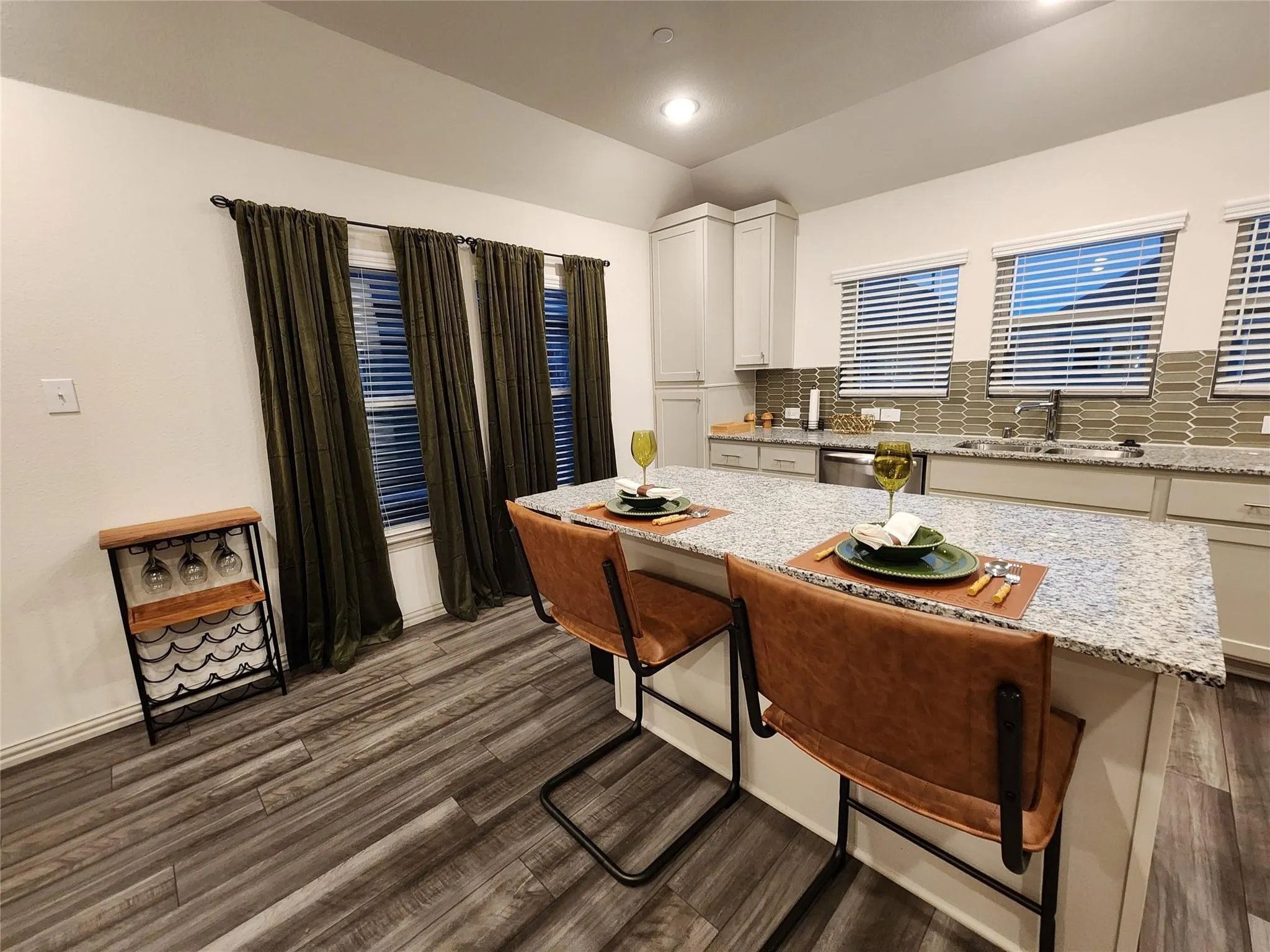 Contemporary kitchen island with a light-toned countertop, wood-finish flooring, recessed lighting, light-colored cabinetry, and a tile backsplash
