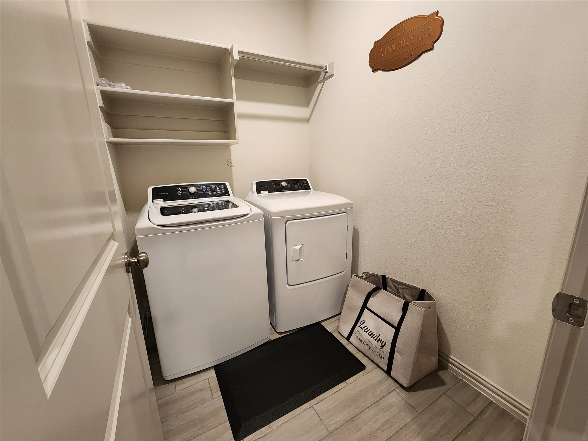 Laundry area with built-in shelving and wood-finish tile flooring