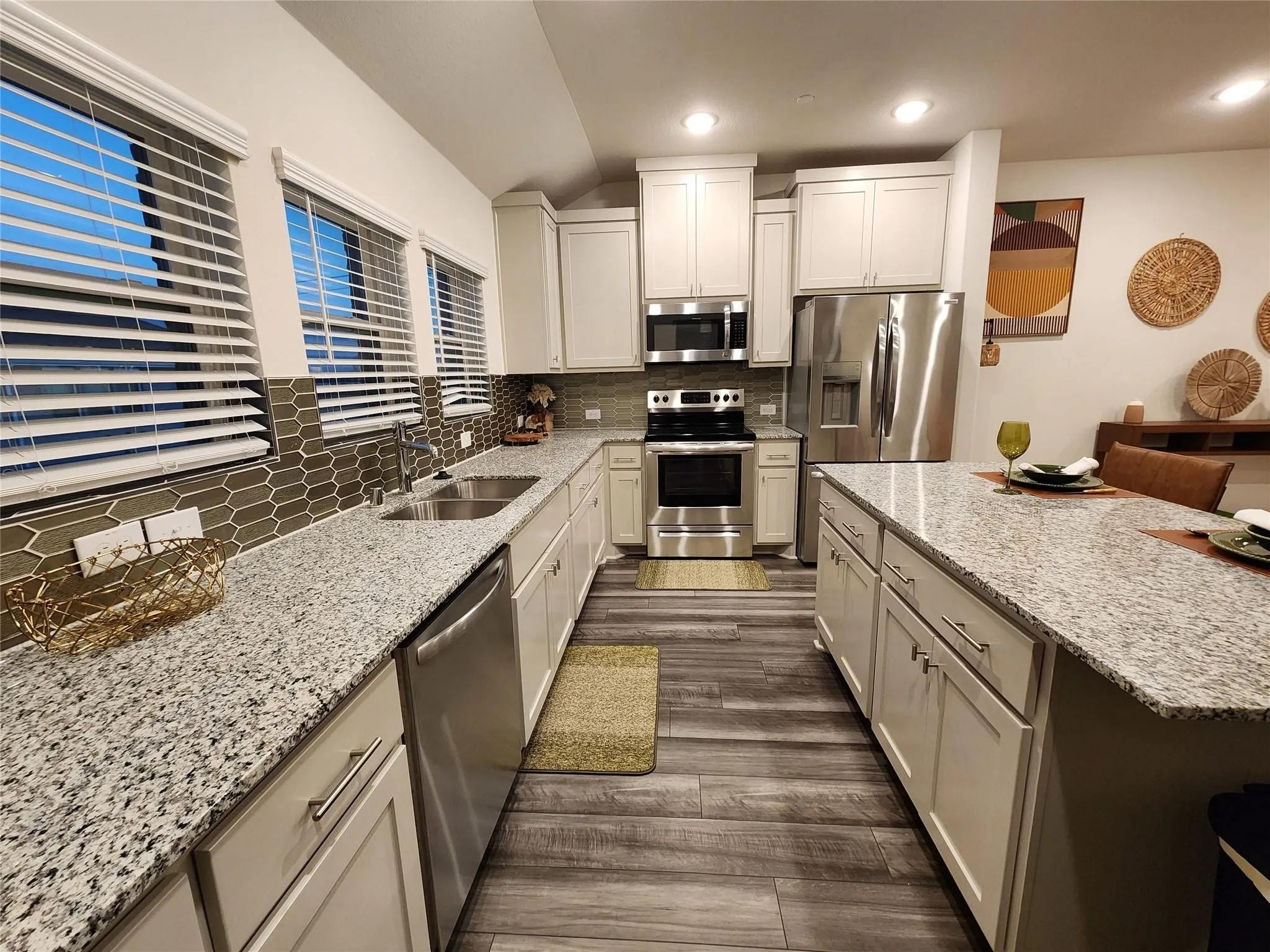 Kitchen featuring white cabinetry, light-colored countertops, stainless steel appliances, and wood-finish flooring
