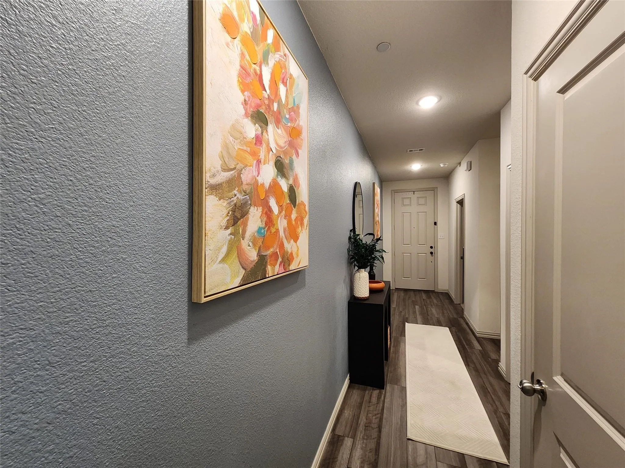 Wood-finish flooring throughout, recessed ceiling lighting, textured wall finish, and a paneled entry door