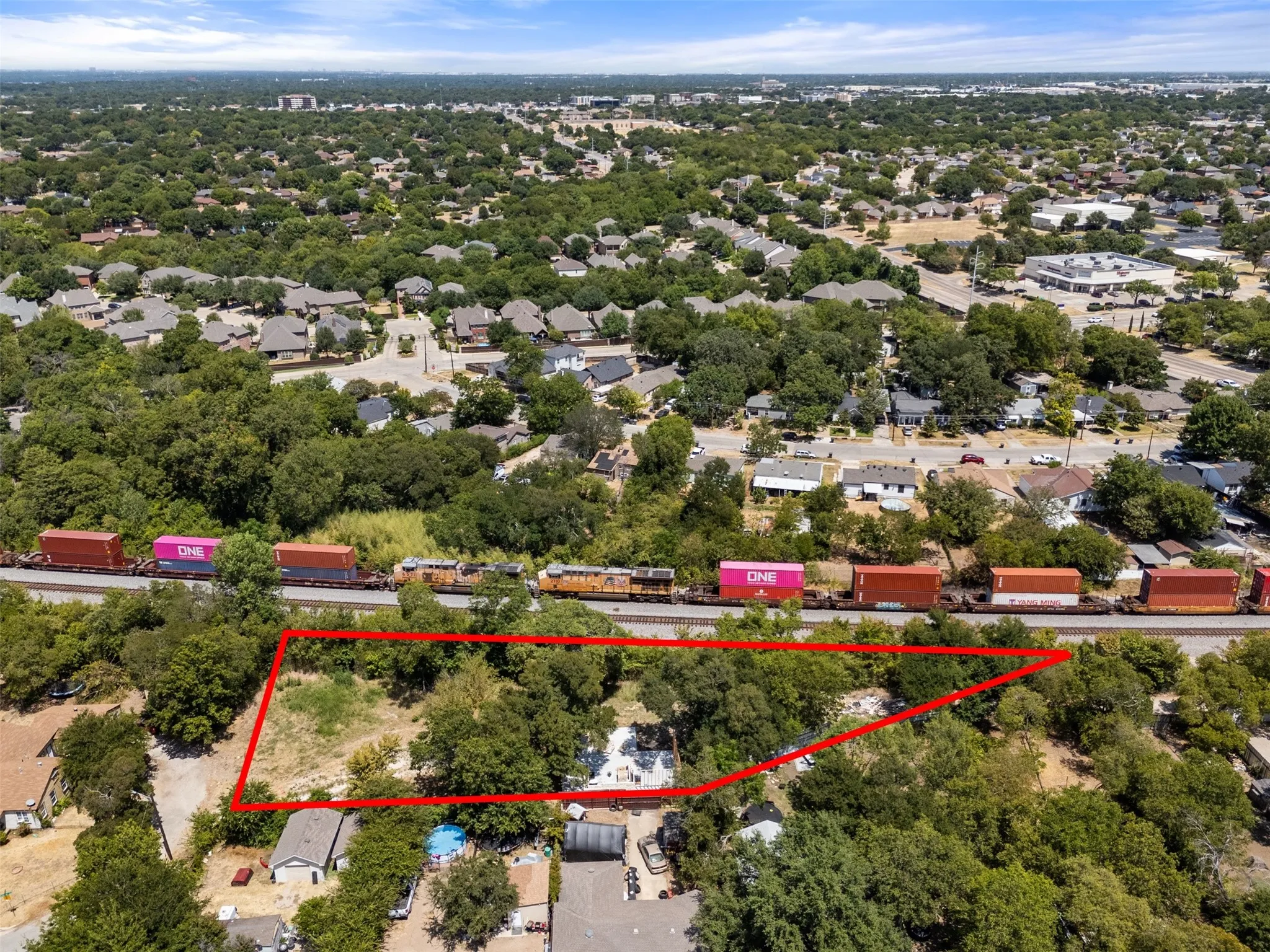 Expansive land parcel with surrounding mature trees and residential properties