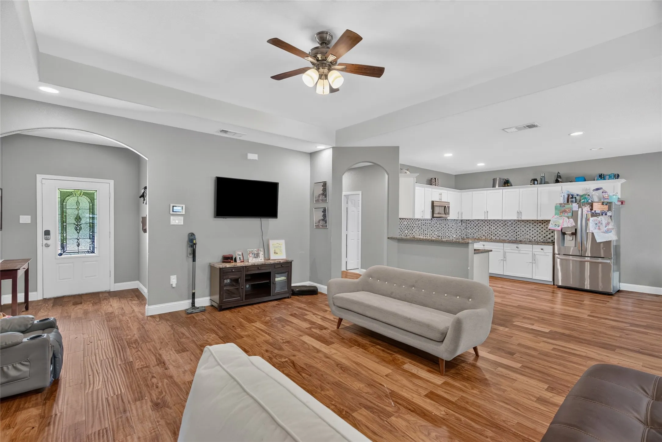 Open-concept living area featuring wood-finish flooring, recessed lighting, and a tray ceiling