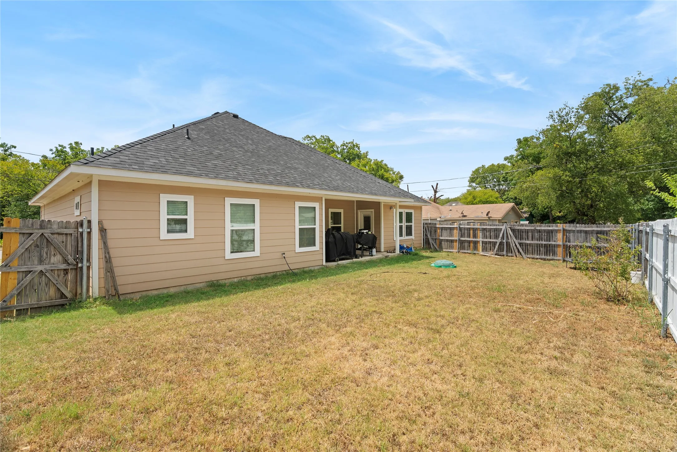 Expansive backyard with a wood privacy fence and a white vinyl privacy fence