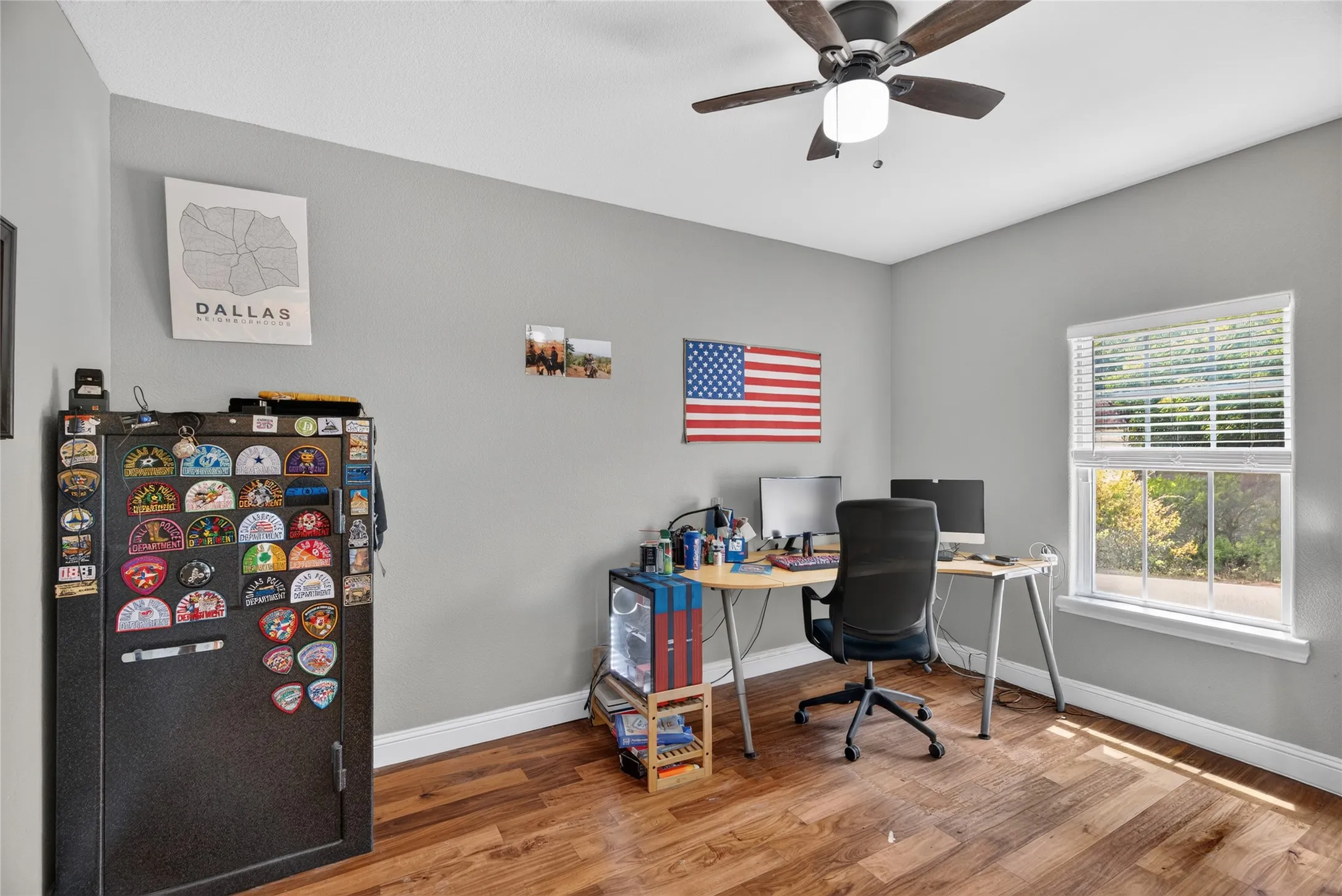 Wood-finish flooring, ceiling fan with integrated lighting, window with blinds, and light gray wall paint