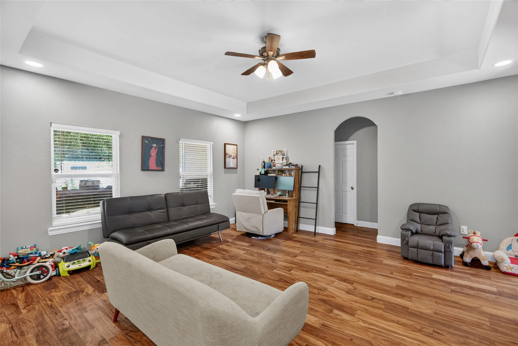 Tray ceiling with recessed lighting and a ceiling fan, wood-finish flooring, and light gray wall paint