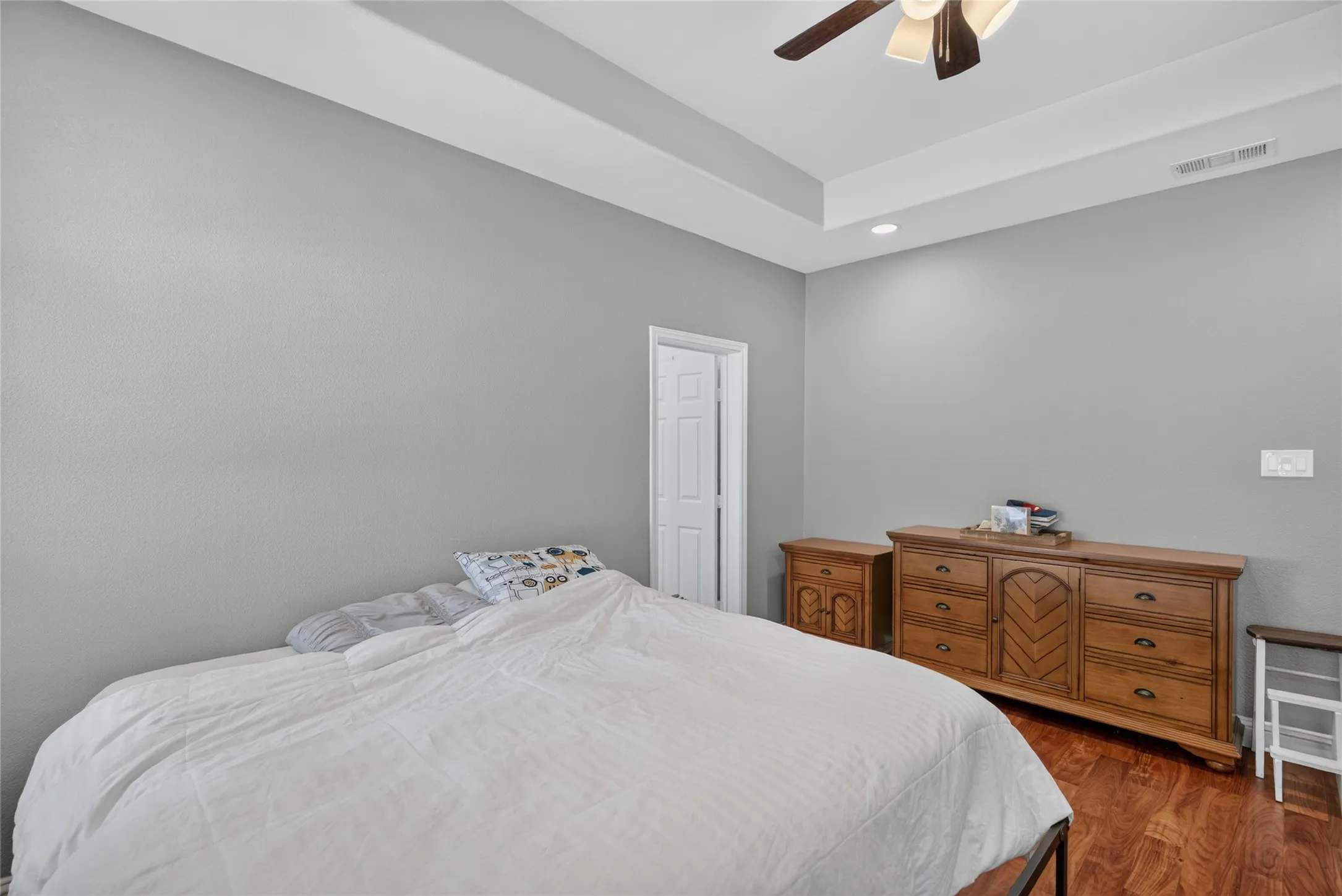 Tray ceiling with recessed lighting, wood-finish flooring, and a ceiling fan