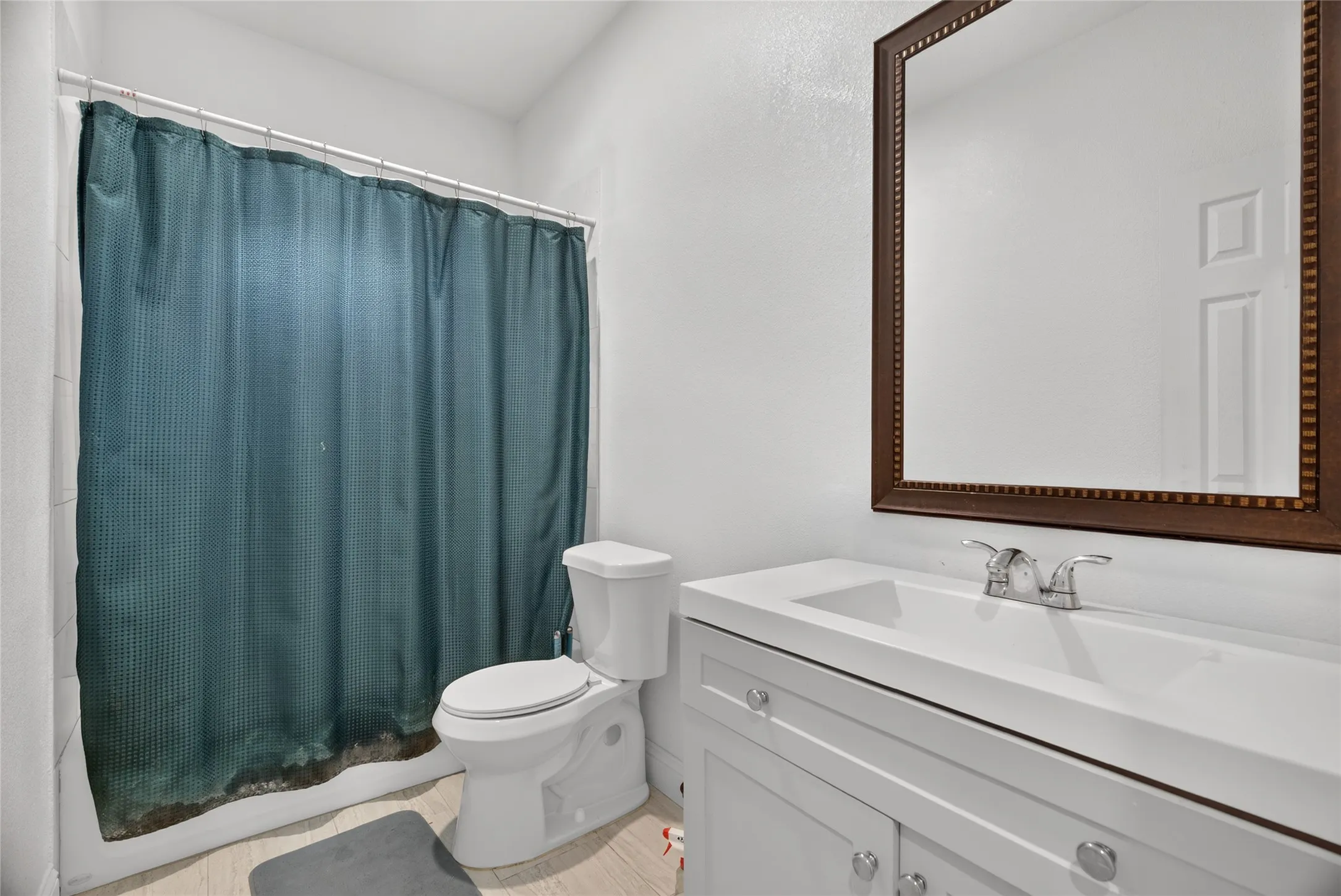 White vanity with integrated sink, chrome faucet, and a decorative framed mirror