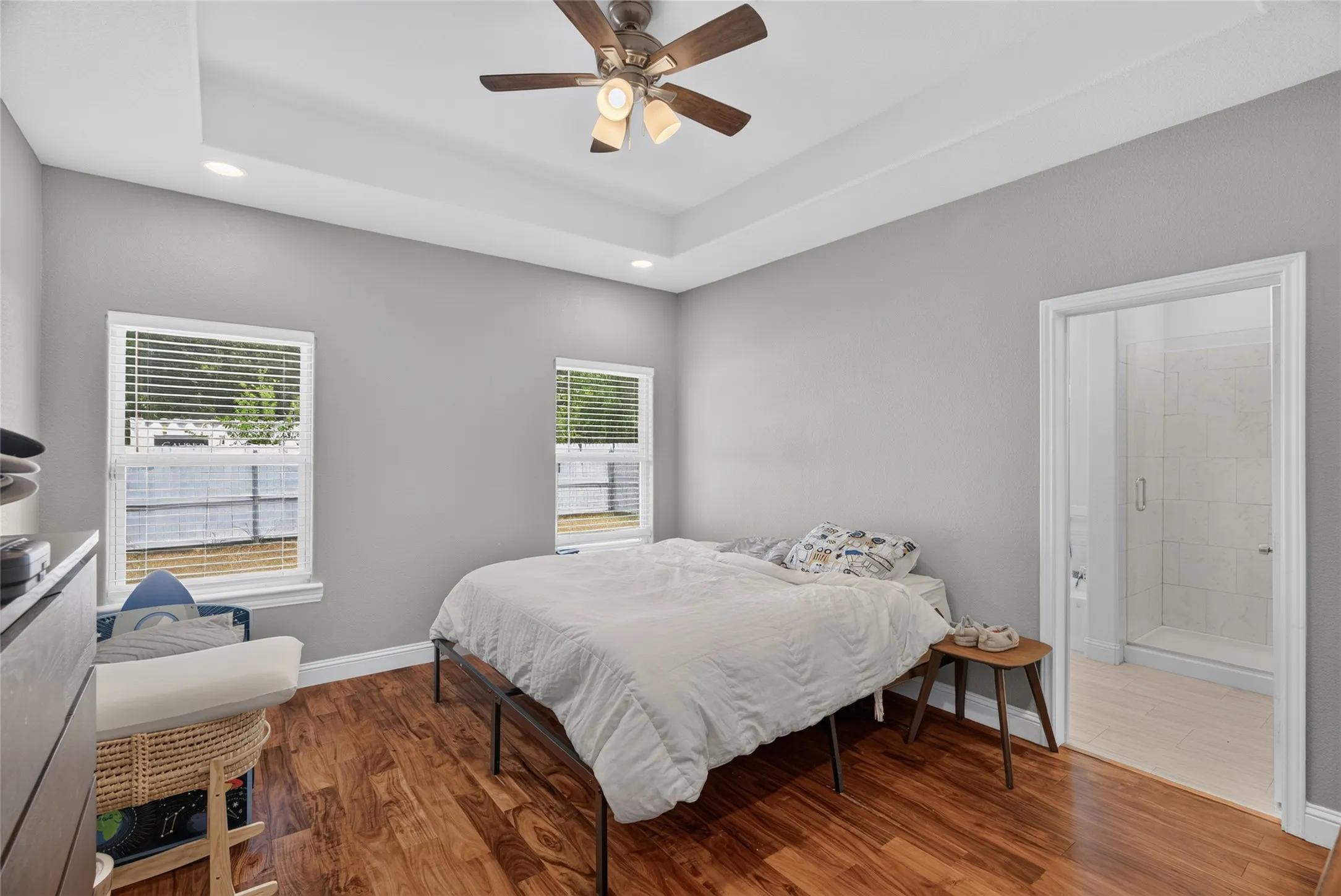 Tray ceiling with recessed lighting, wood-finish flooring, and a ceiling fan