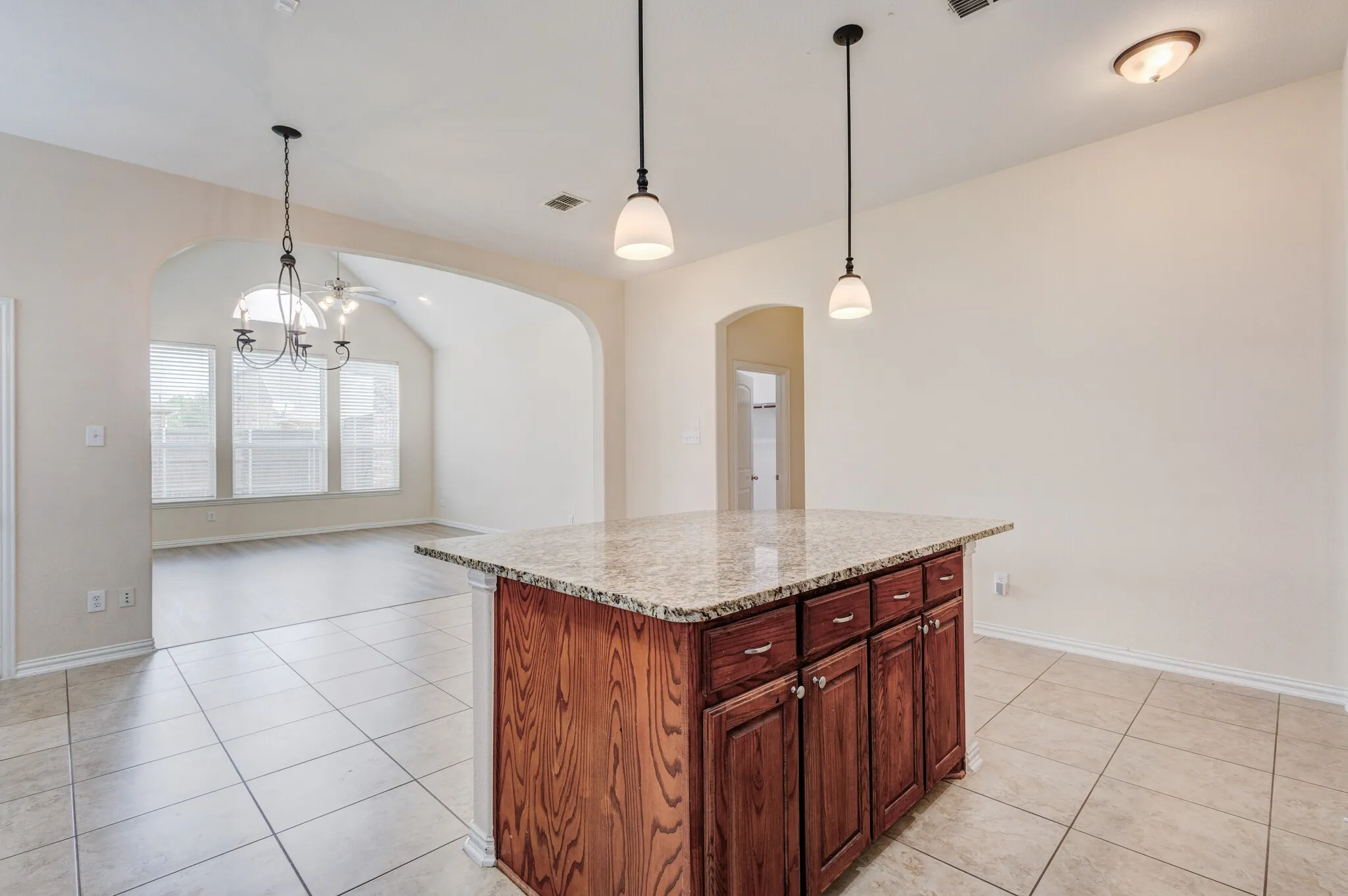 Kitchen island with wood-finish cabinetry and a light-colored stone countertop