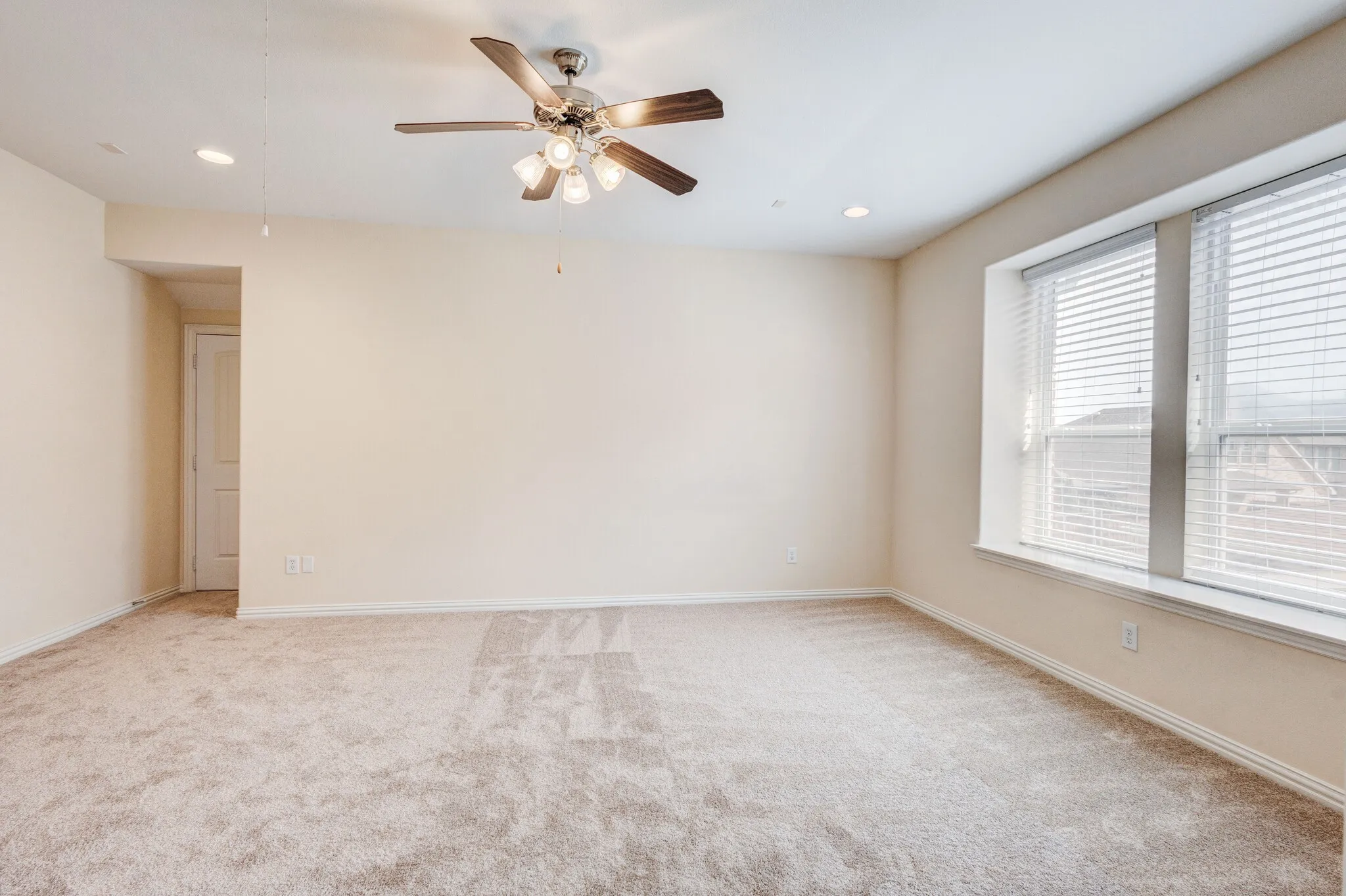 Recessed lighting, ceiling fan with light fixture, window with horizontal blinds, carpeted flooring, and a paneled interior door