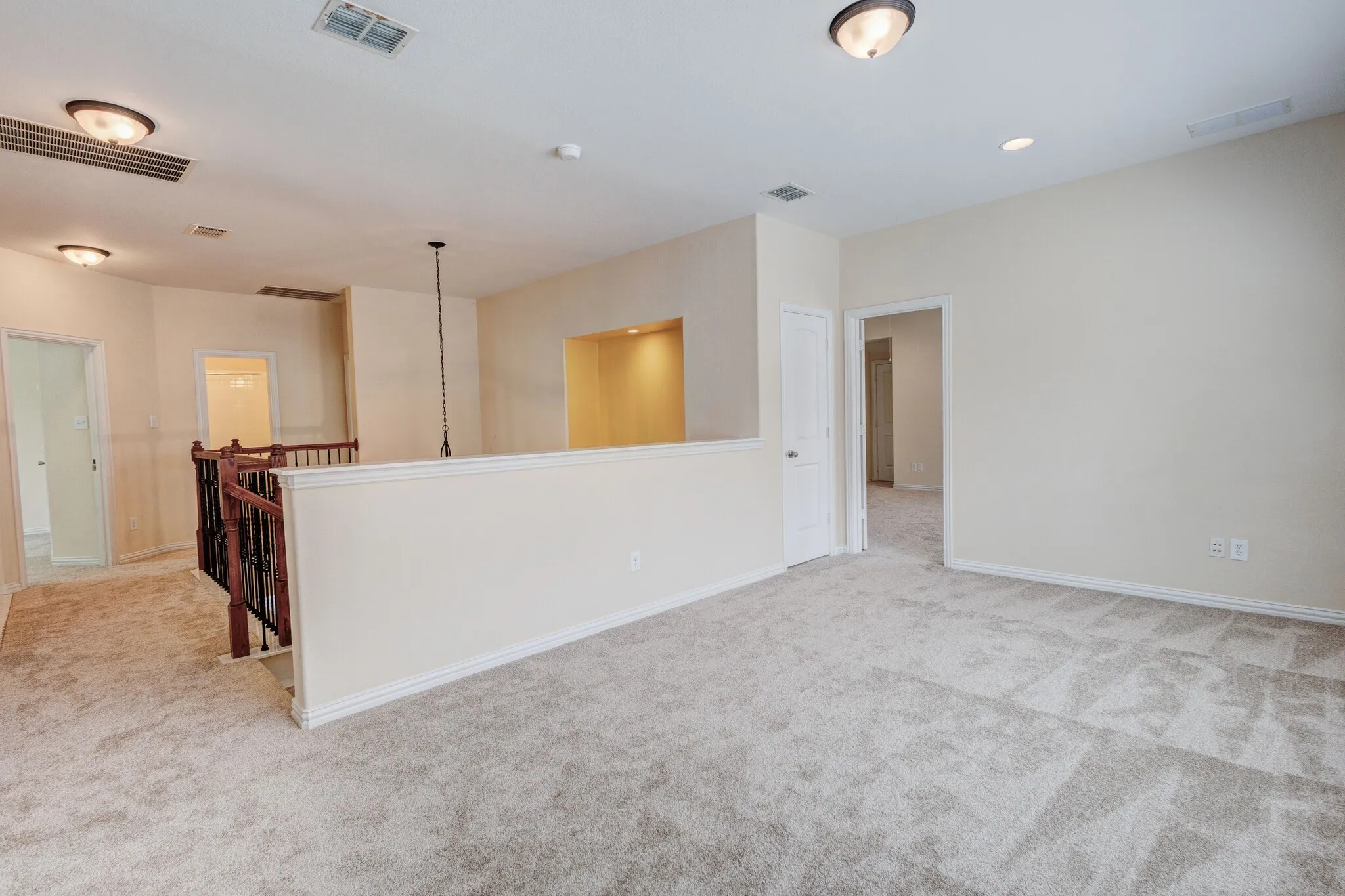 Carpeted landing area featuring a wooden and wrought iron staircase, recessed lighting, and a built-in illuminated niche