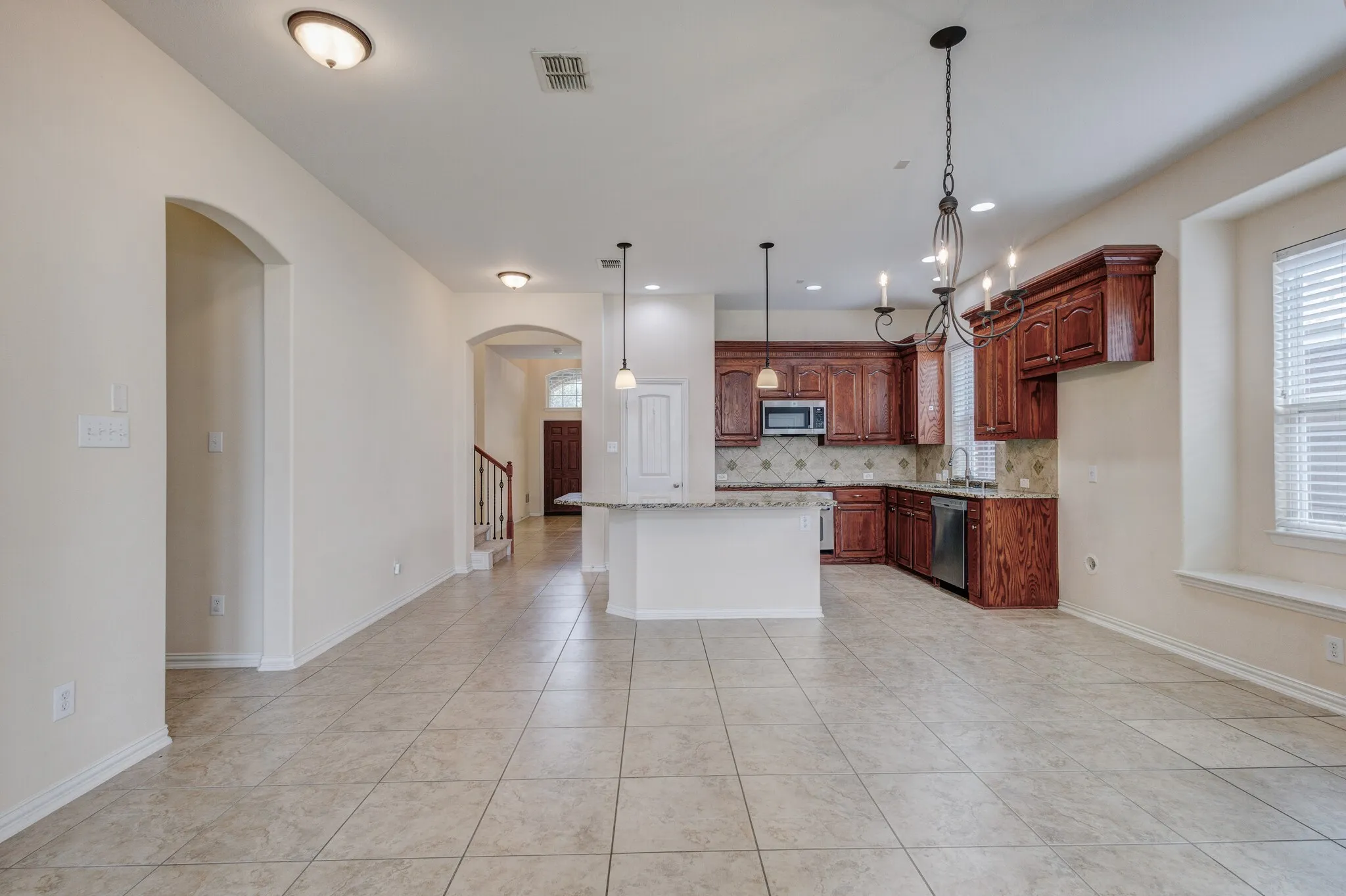 Tile flooring throughout, an open-concept kitchen with wood-finish cabinetry, a built-in microwave, and stainless steel appliances