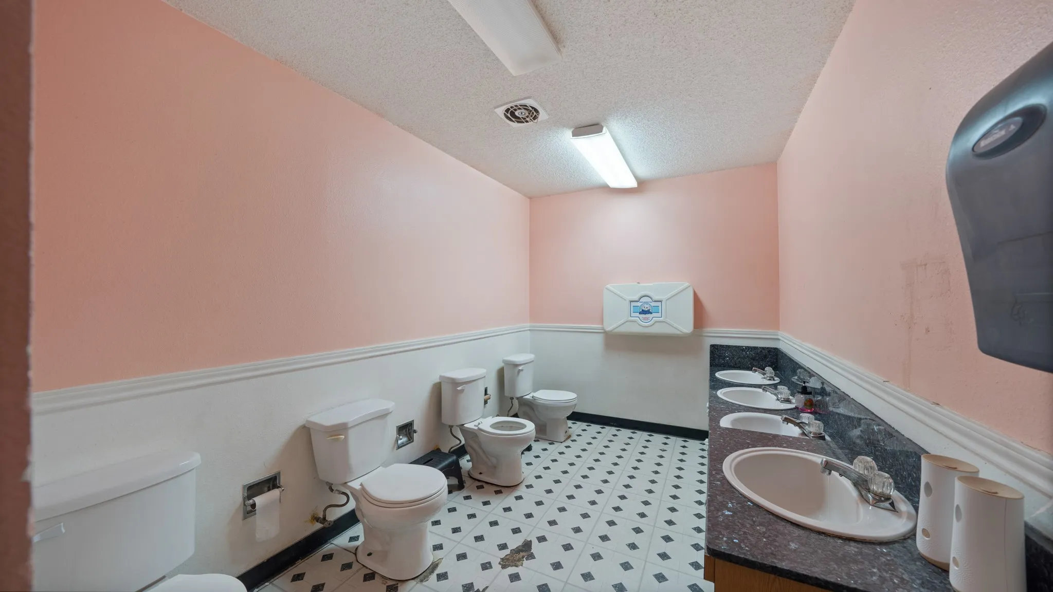 Tile flooring with a geometric pattern, extensive counter space with multiple sinks, and a wall-mounted baby changing station