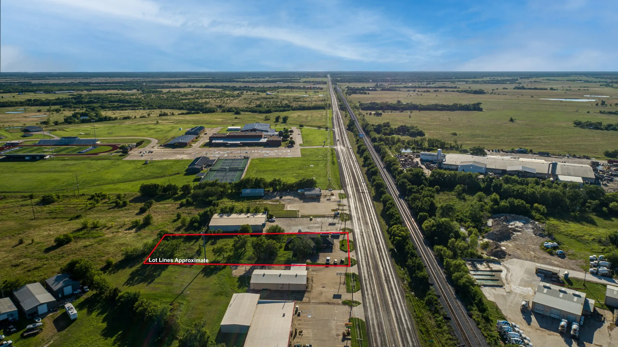 Expansive land parcel with surrounding commercial structures and a distant institutional complex