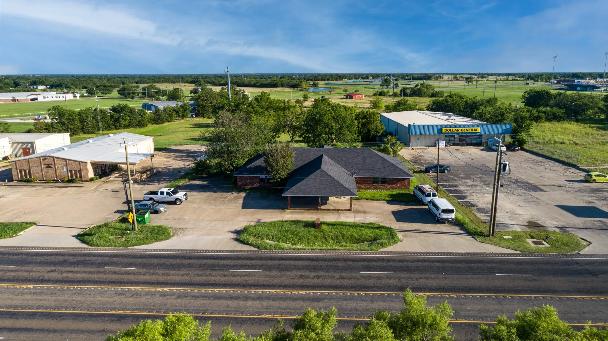 Commercial property featuring a dark shingle roof, paved parking, and a prominent roadside location