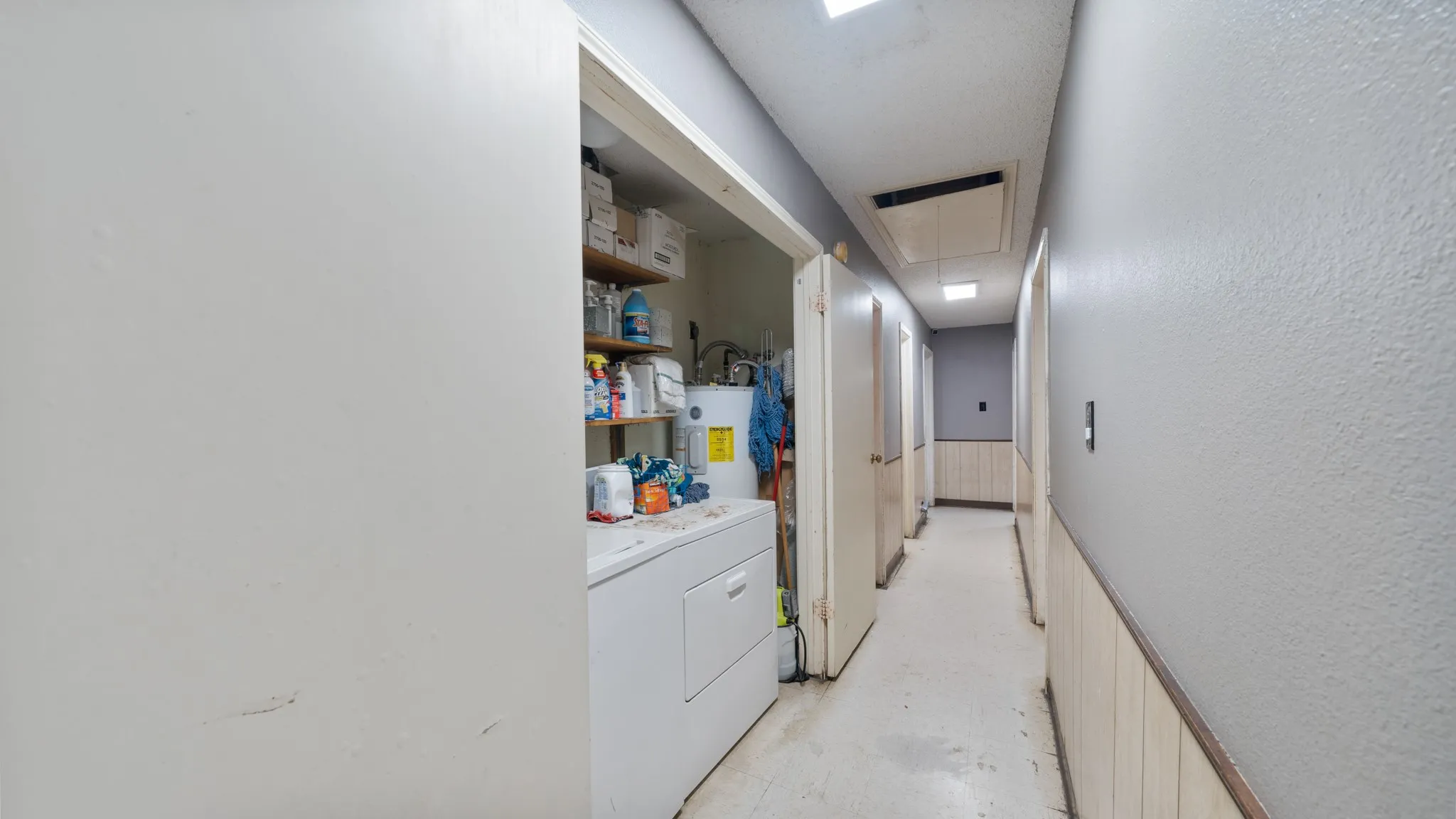 Laundry area with built-in shelving, water heater, and overhead lighting