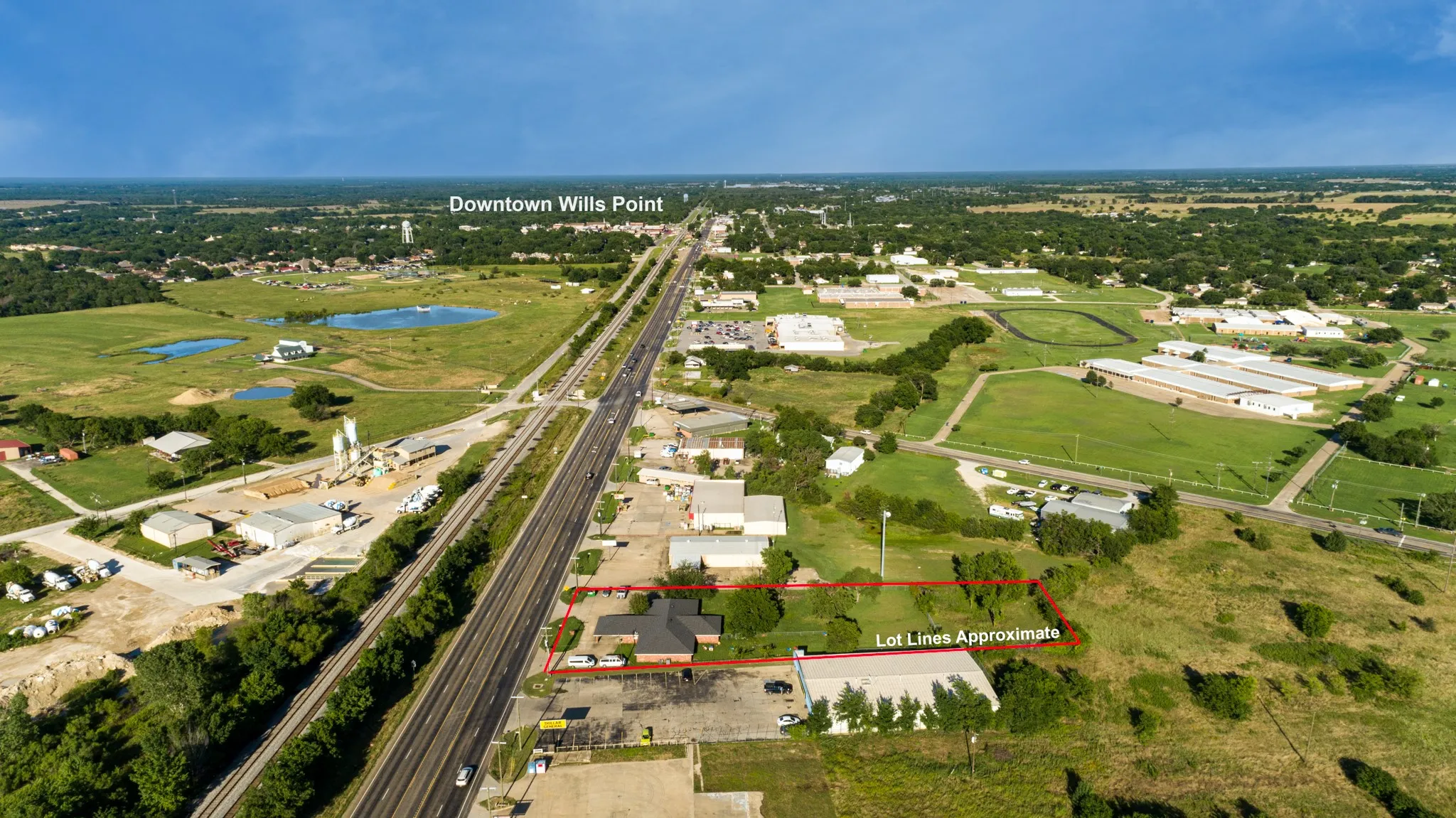 Aerial perspective of the property, featuring a building with a dark roof and a surrounding paved area