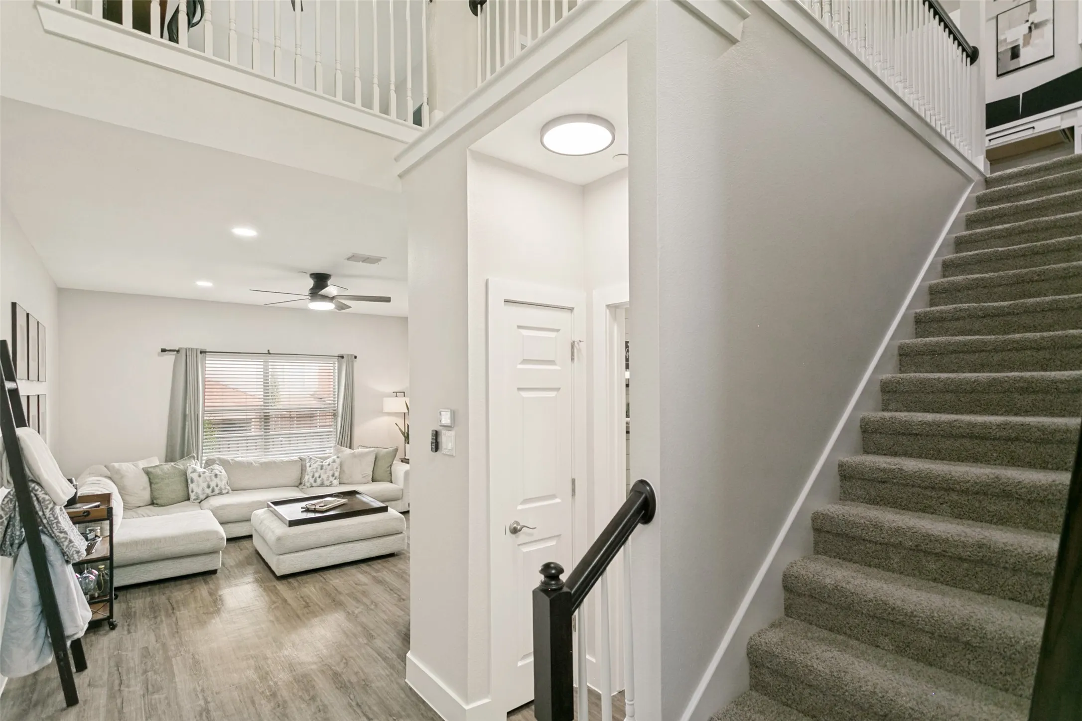 Carpeted staircase with black handrail, wood-finish flooring, recessed lighting, and a ceiling fan