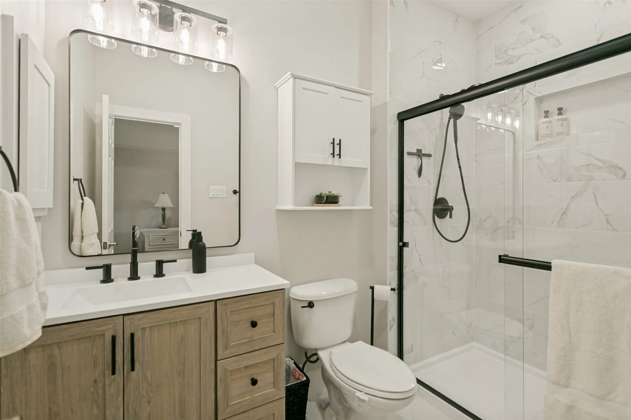 Wood-finish vanity with a white countertop and matte black fixtures