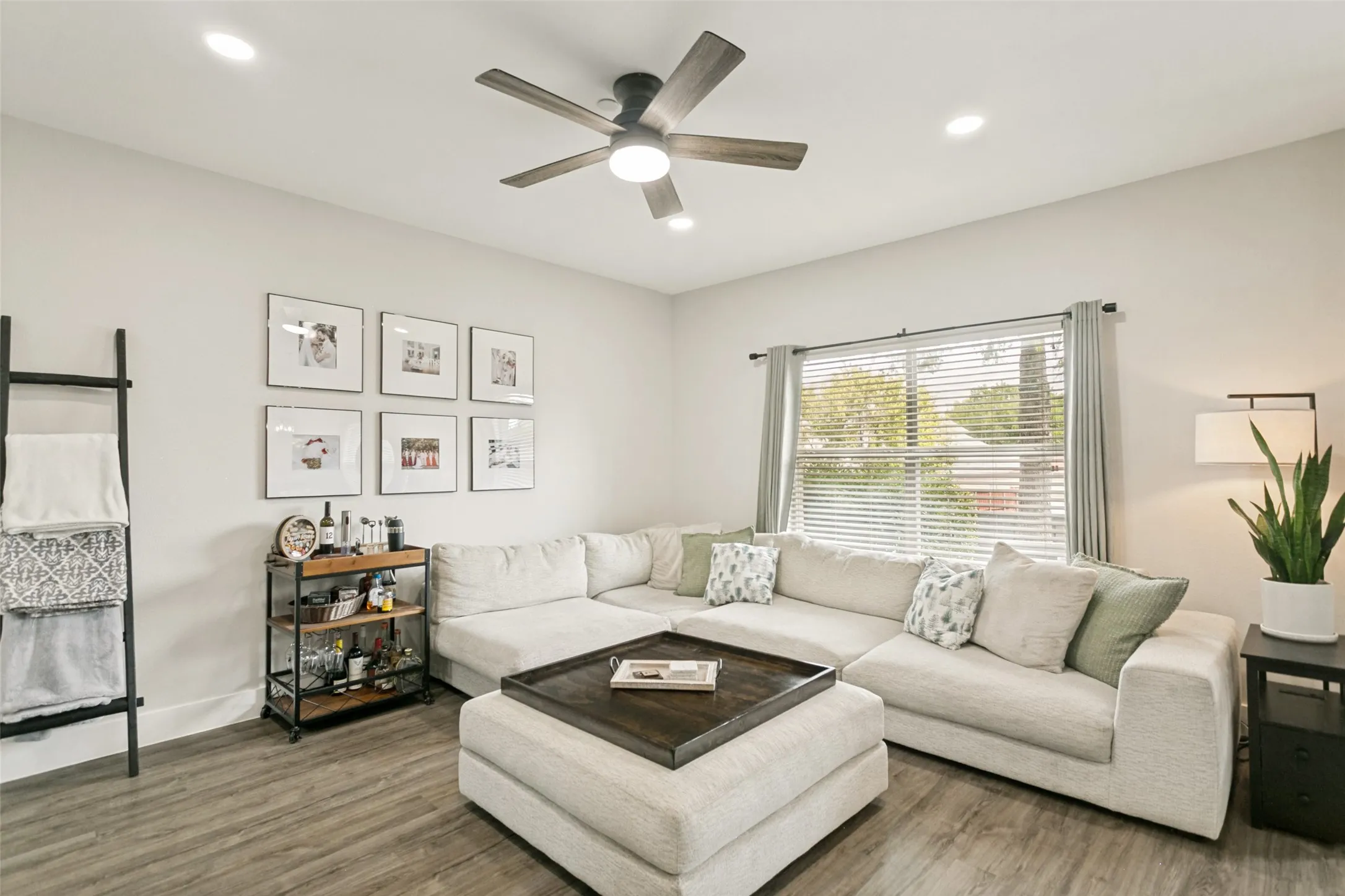 Recessed ceiling lighting, wood-finish flooring, ceiling fan, and a large window with blinds