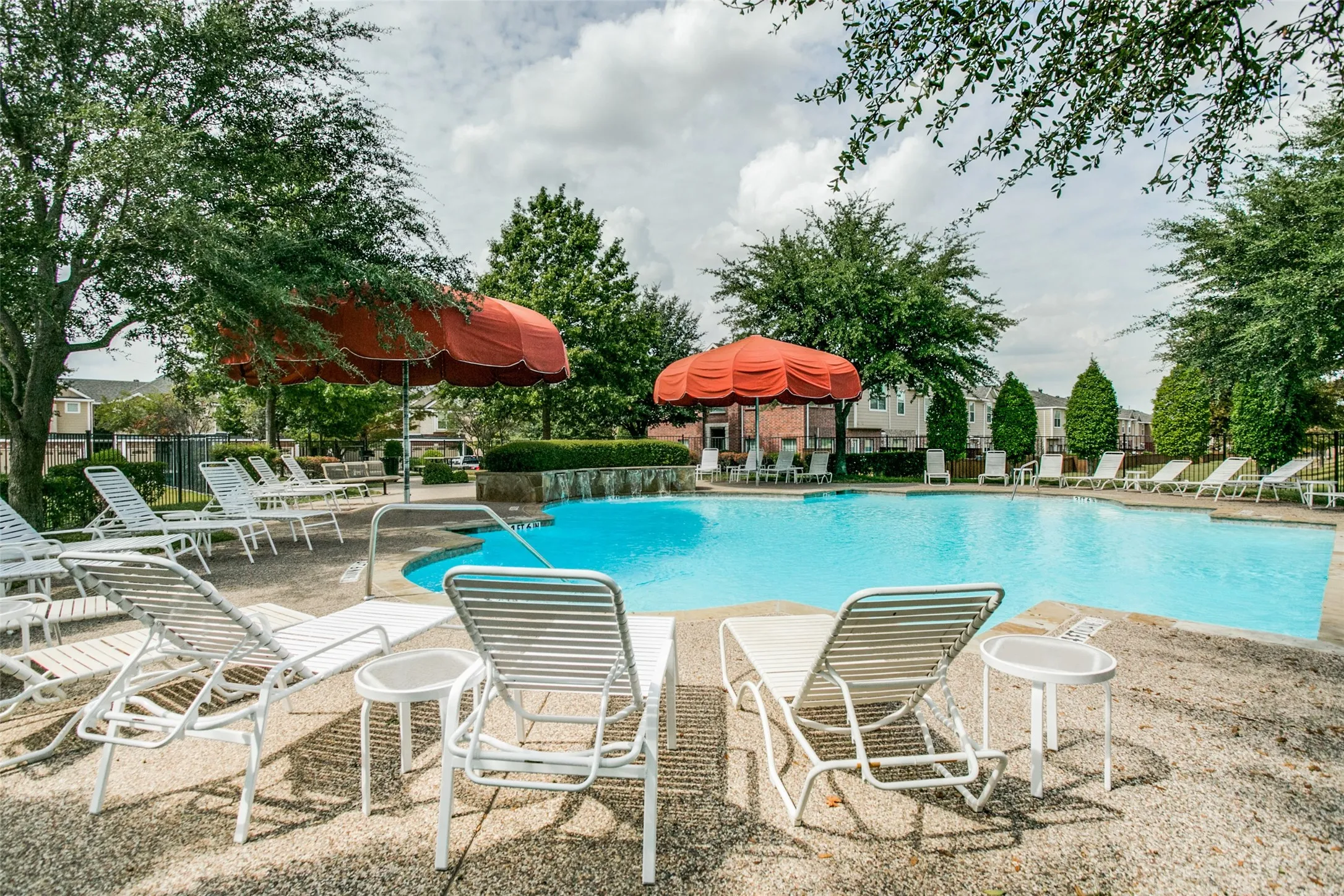 Resort-style pool area featuring a blue-tiled swimming pool, a stone-finish pool deck, and integrated water features