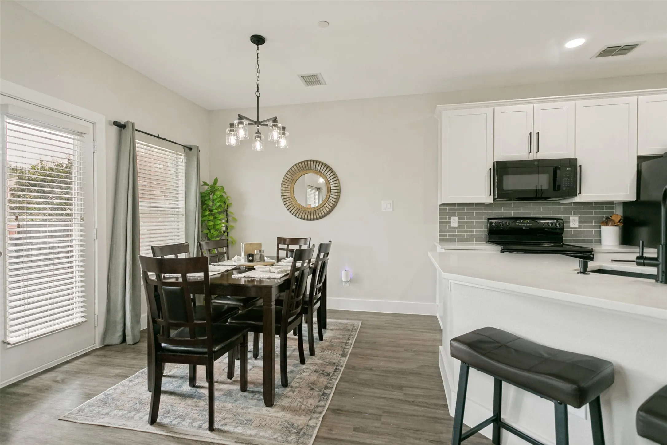 Open-concept dining area with wood-finish flooring, a modern chandelier, and access to an exterior doorway