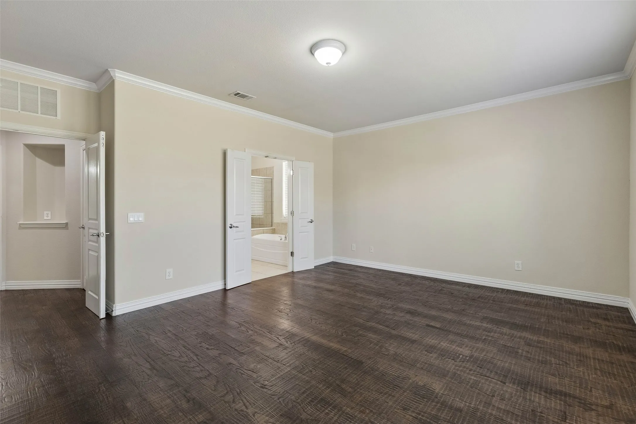 Wood-finish flooring, crown molding, double doors, and a built-in ceiling light fixture