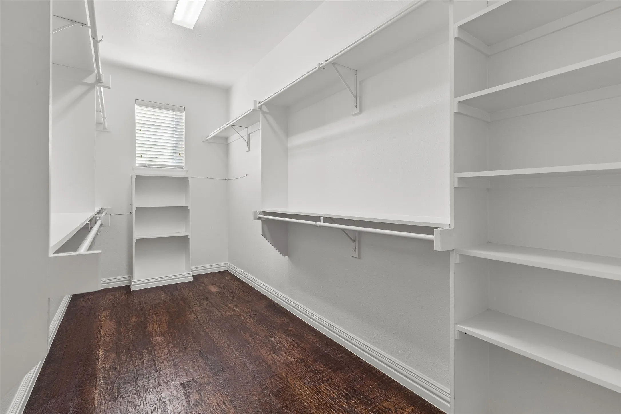 Built-in shelving units, wood-finish flooring, recessed lighting, and a window with blinds