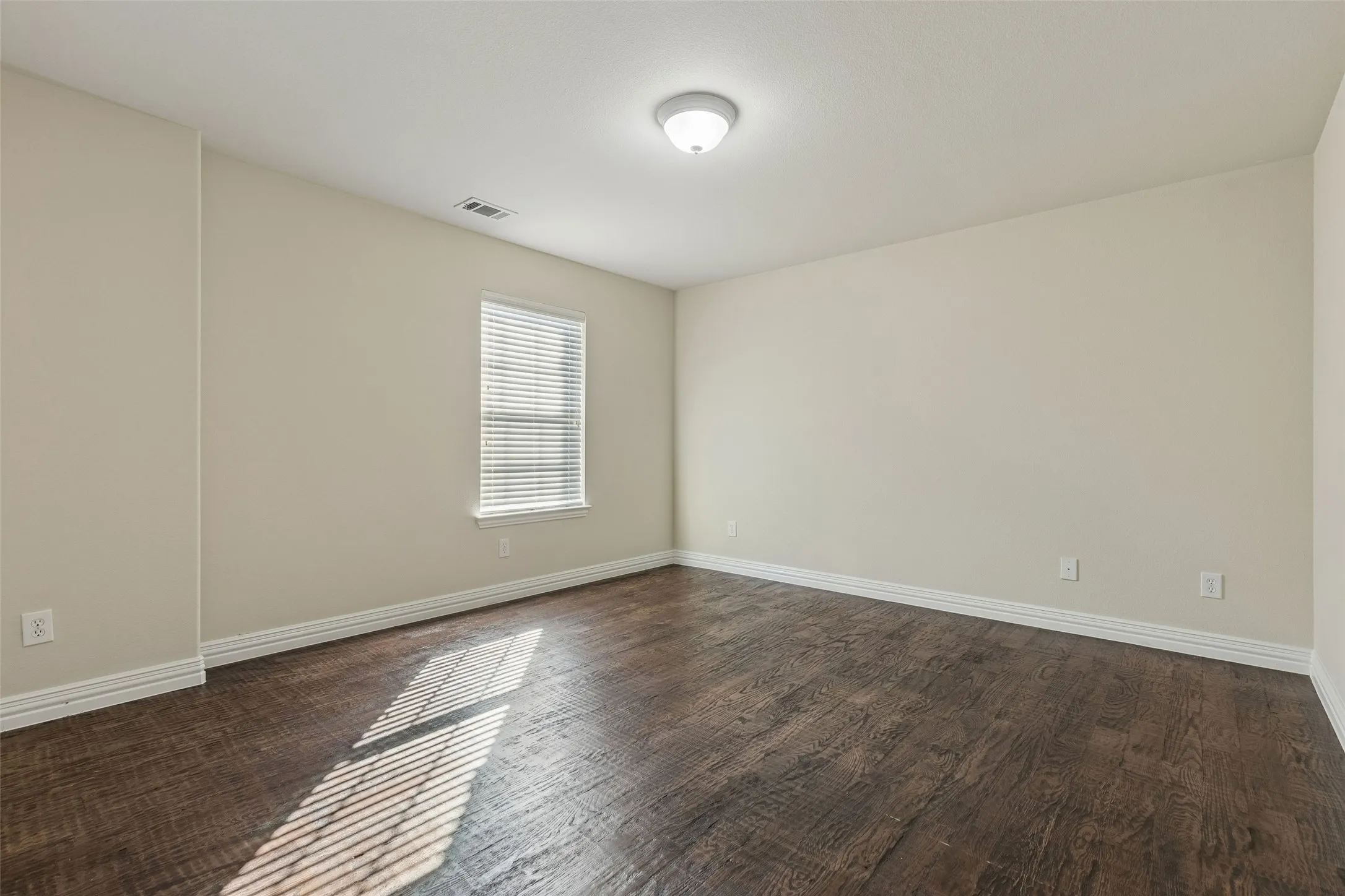 Recessed window with horizontal blinds, overhead ceiling light fixture, wood-finish flooring, and light-toned walls