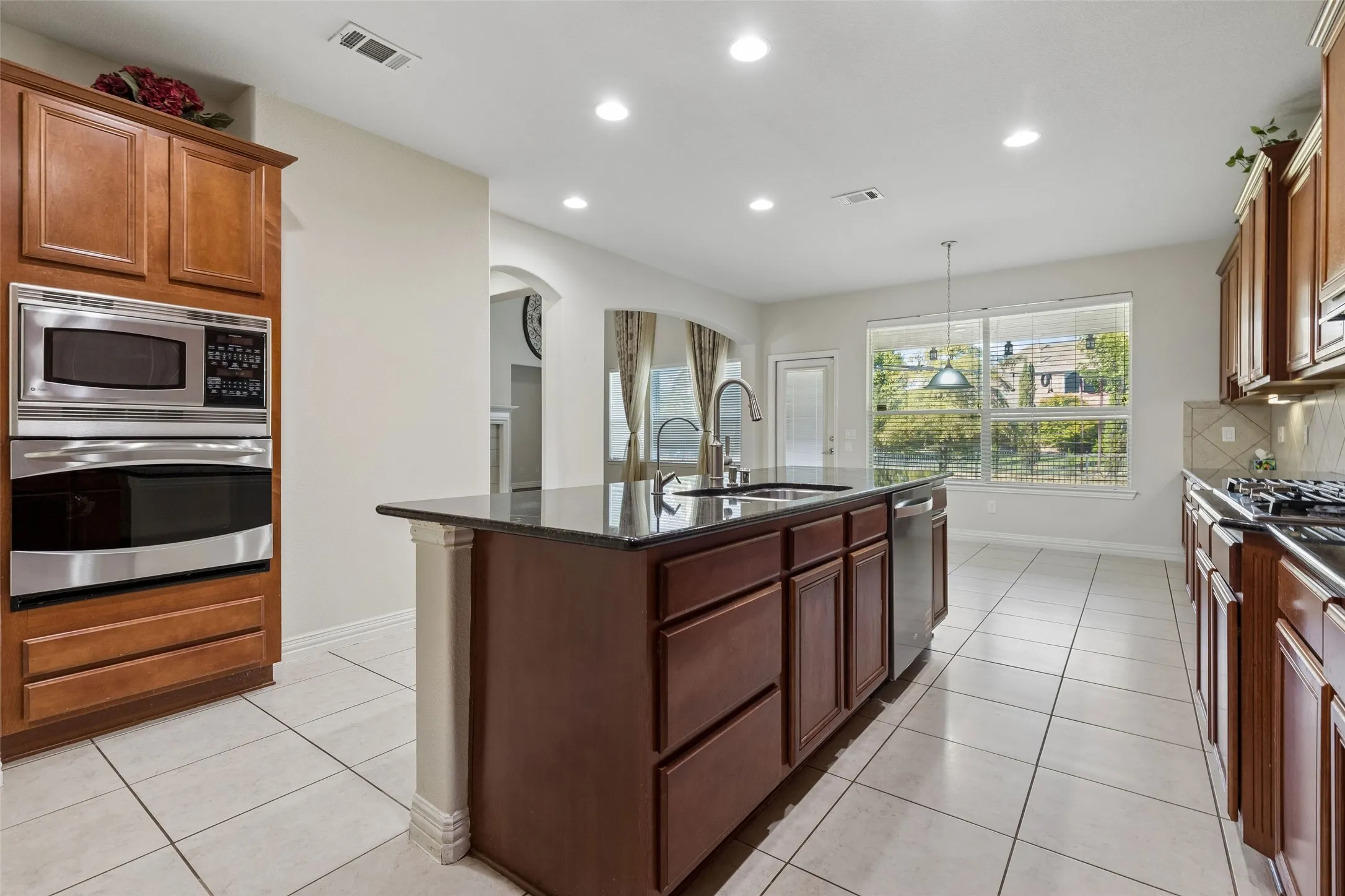 Kitchen featuring a central island, integrated stainless steel appliances, wood cabinetry, and a tile backsplash