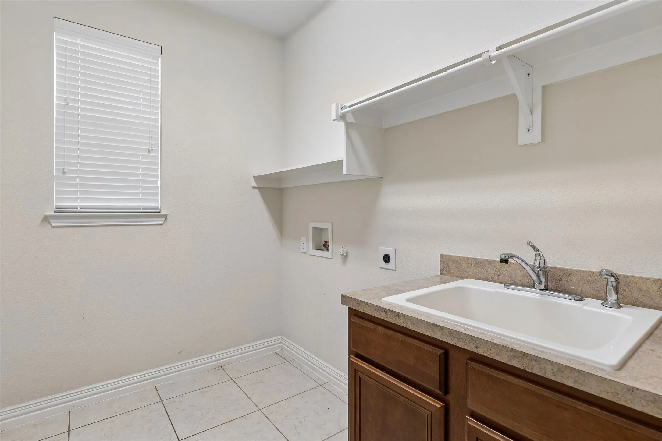 Built-in cabinetry with a utility sink, laminate countertop, and tile flooring