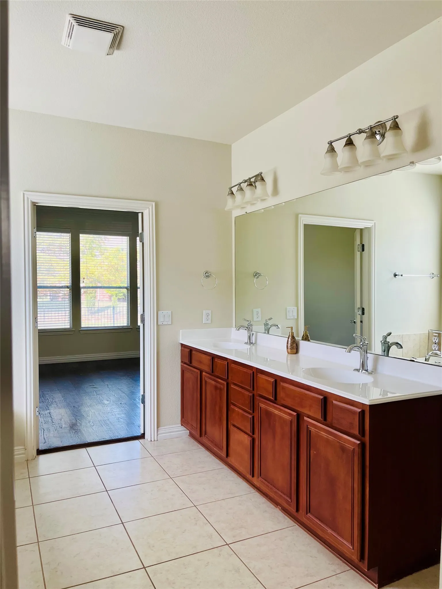 Dual vanity with wood-finish cabinetry, white countertops, and tile flooring