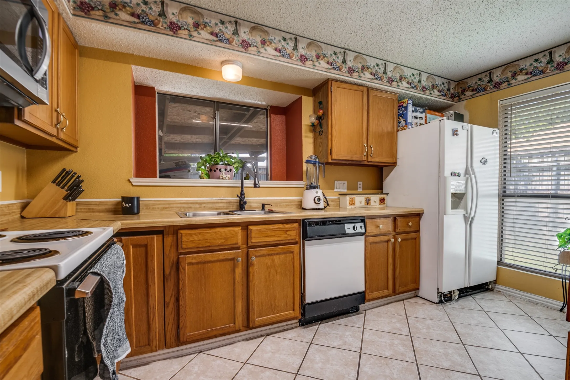 Kitchen featuring wood cabinetry, laminate countertops, a built-in microwave, and tile flooring