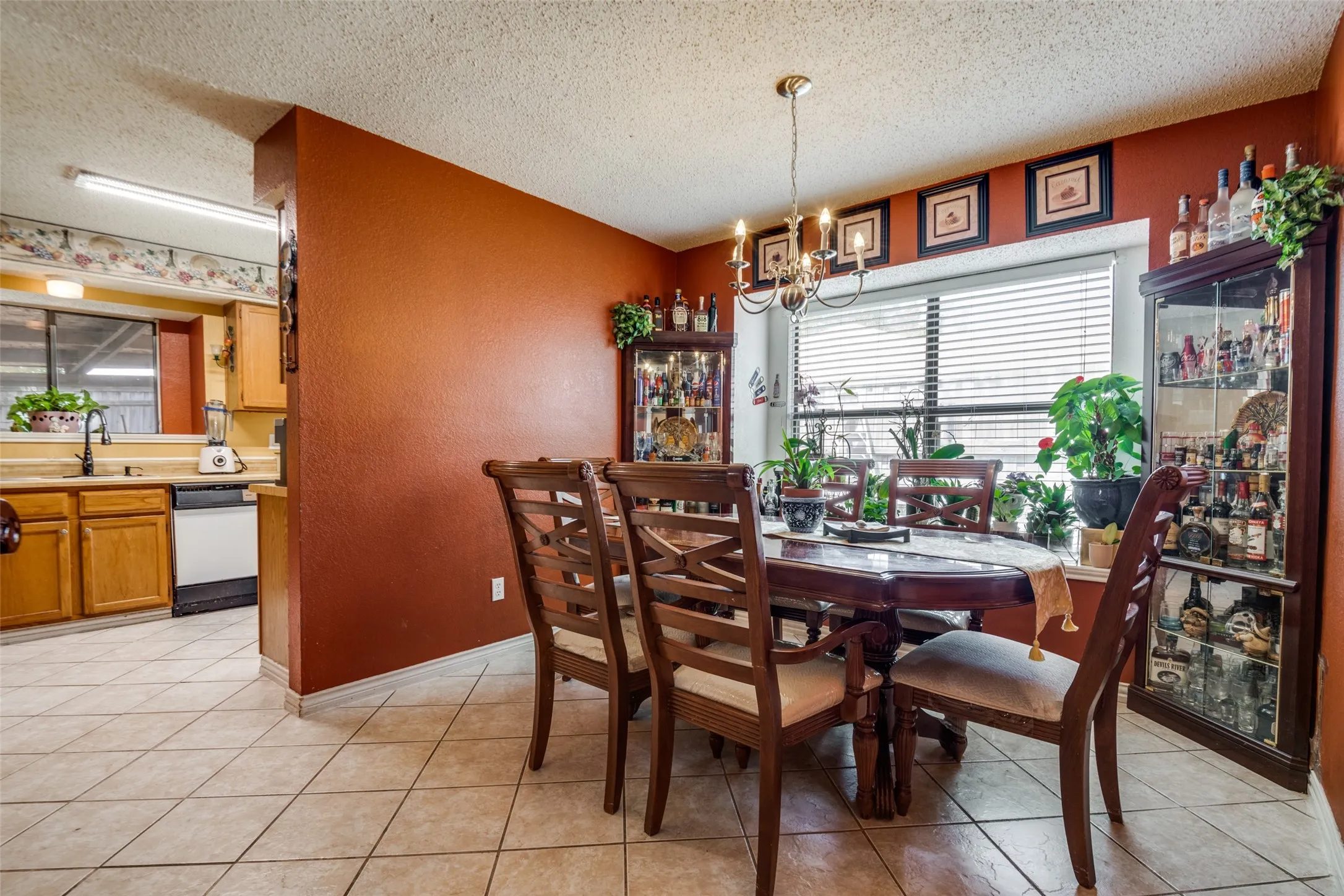 Tile flooring, window with blinds, chandelier lighting, recessed wall, and built-in display cabinetry