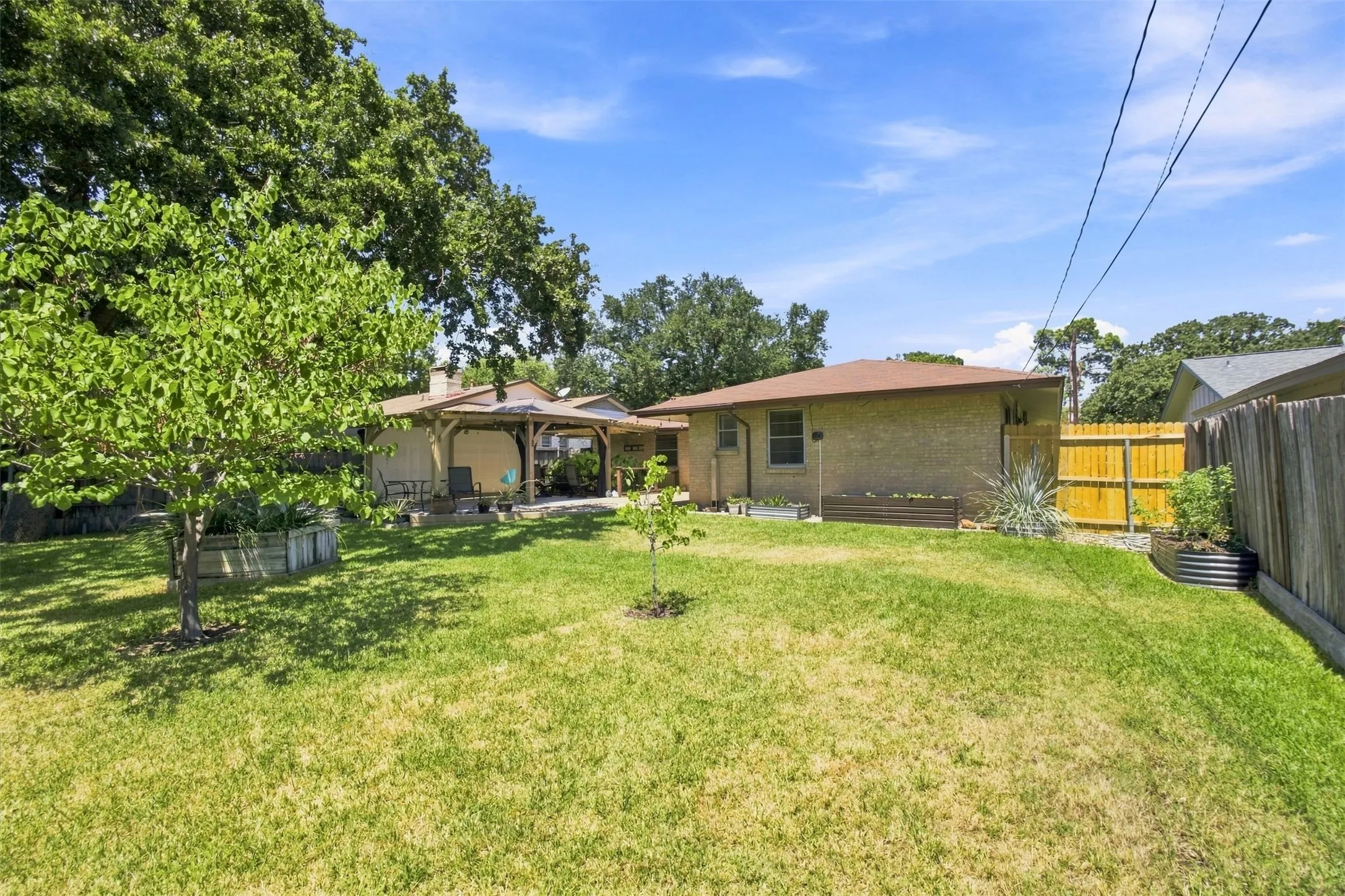 Expansive green lawn with mature trees and a covered patio structure