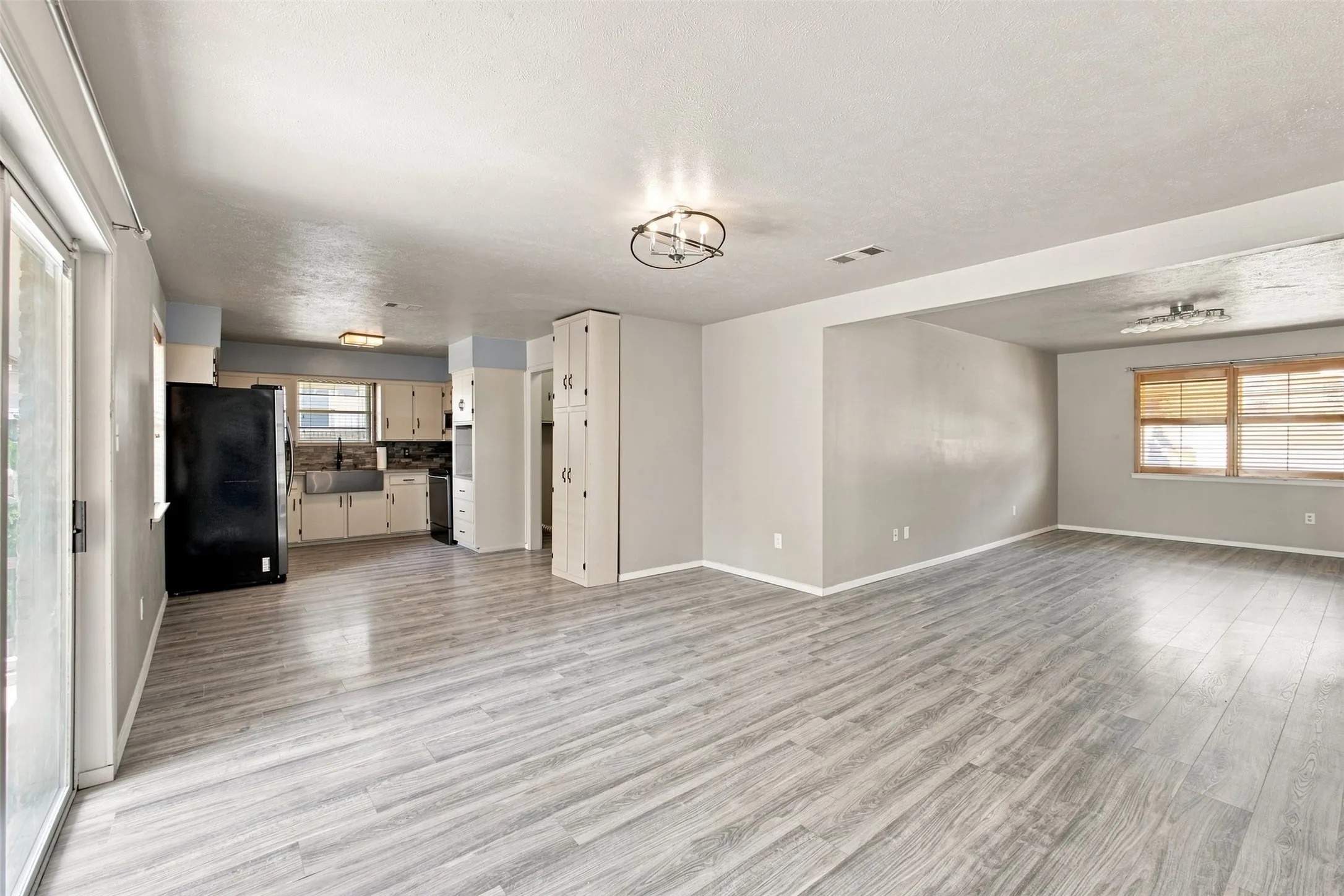 Expansive living area with wood-finish flooring, recessed lighting, and a modern ceiling fixture