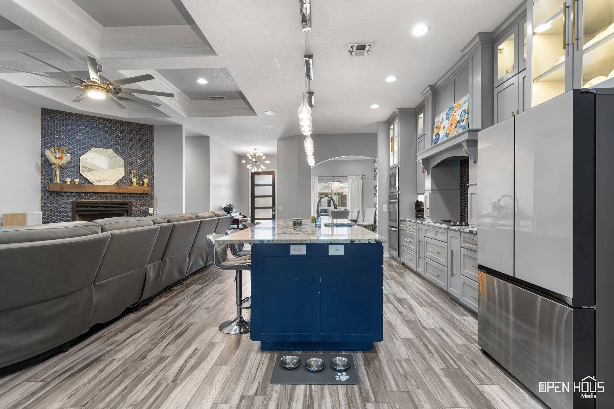 Spacious kitchen featuring an island with a built-in sink, stainless steel appliances, and extensive grey cabinetry