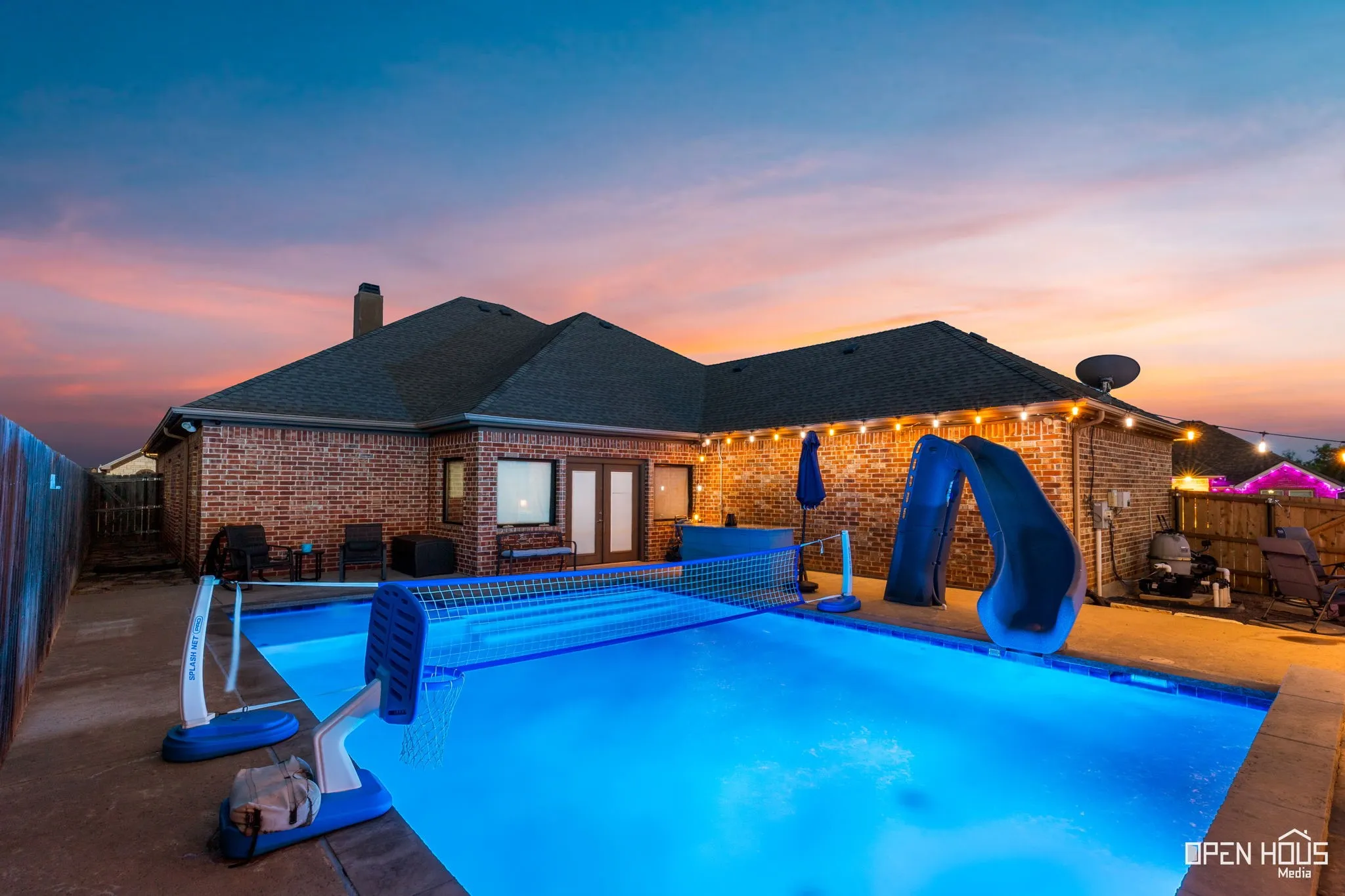 Brick exterior with a dark shingle roof and a built-in swimming pool