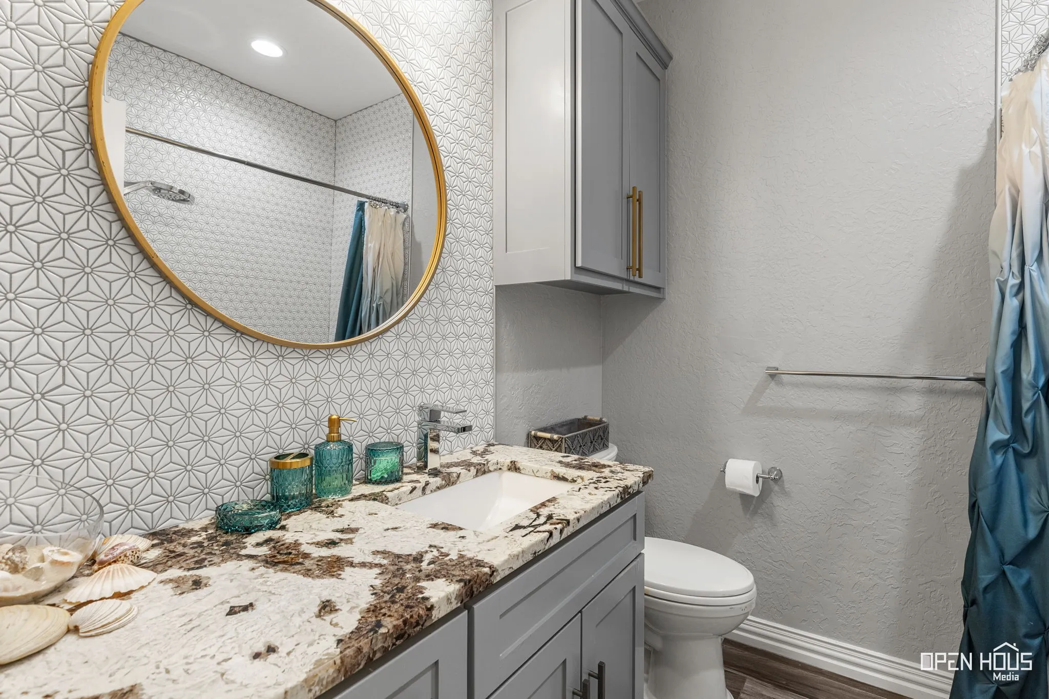 Bathroom vanity with an integrated rectangular sink, stone countertop, and gray cabinetry with gold-tone hardware