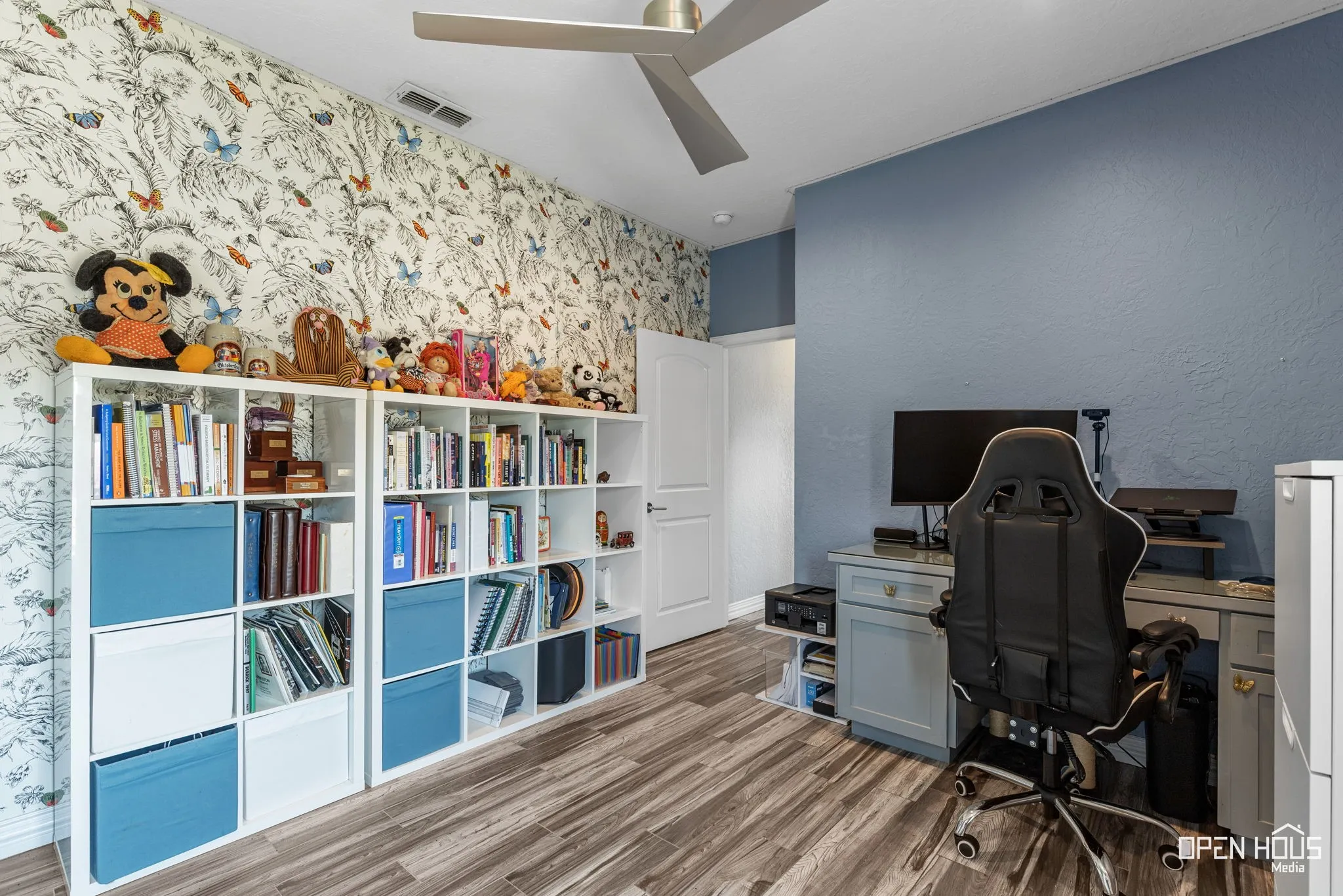 Tile flooring, accent wall with decorative wallpaper, ceiling fan with light fixture, and white interior door