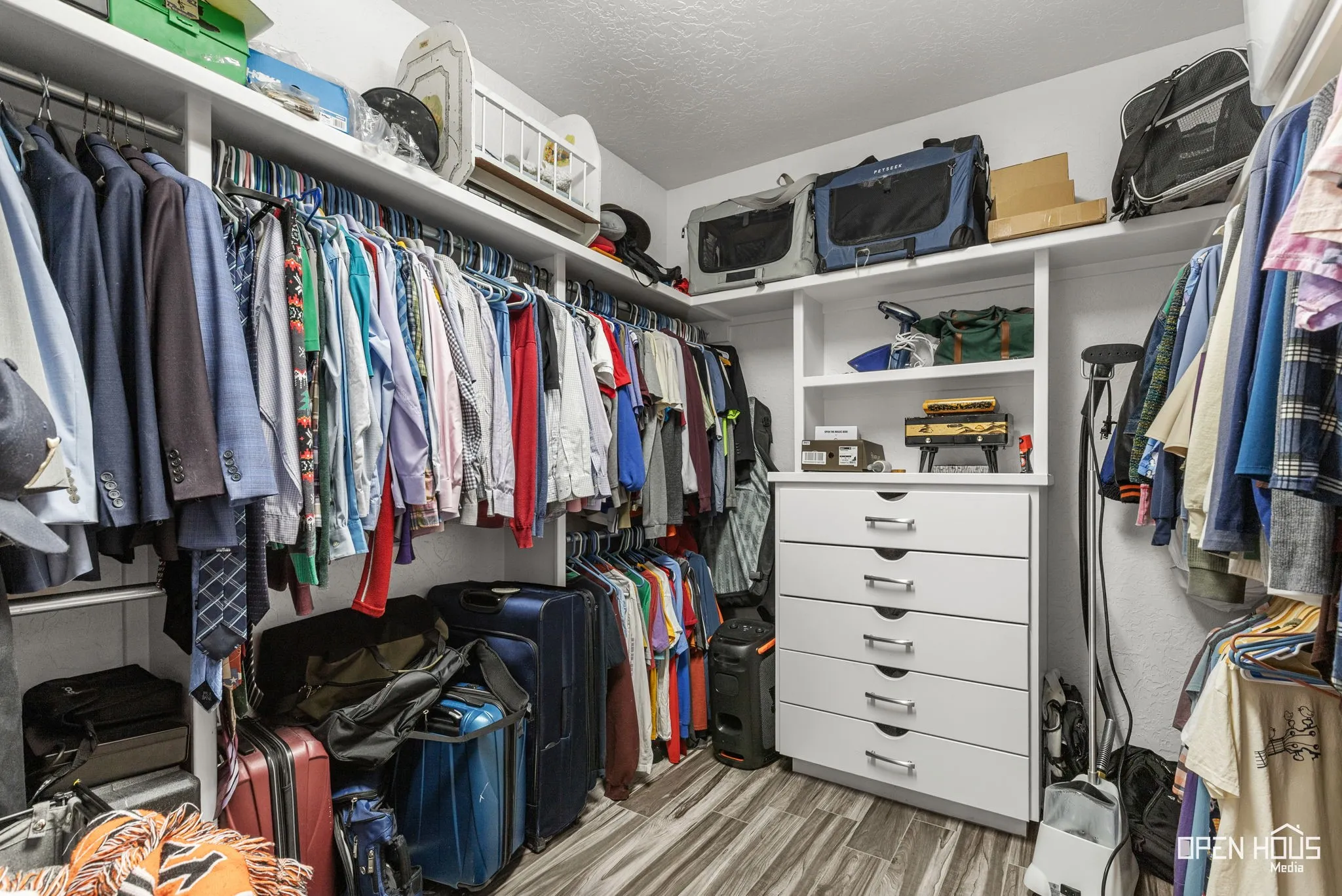 Built-in closet system featuring extensive shelving, multiple hanging rods, an integrated chest of drawers, and tile flooring